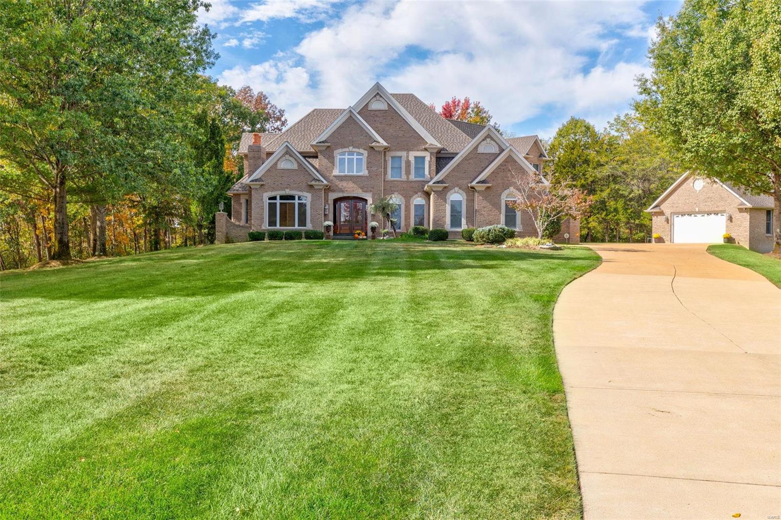 Superb craftsmanship & distinctive architectural elements define this magnificent 1.5-sty estate, boasting approx. 5000 sq ft of living space! Located in a gated community & sits on 2.15 acres. Hosting a 5-car garage, the detached garage is constructed on a foundation adding additional storage space. Impressive marble foyer highlights the dramatic sweeping staircase leads to the distinctive tray & box-beam ceilings in the cherry-clad office with fireplace. Formal dining room. The stunning great room includes wet bar, cast stone fireplace & floor to ceiling wall of windows showcasing views of the resort-style heated salt water pool. Designer kitchen with custom cabinetry, granite countertops & commercial grade appliances adjoins breakfast room & vaulted hearth room. Spacious primary bedroom suite offers retreat-like luxury bath & designer spacious walk-in closet. Front & rear staircases access 3 additional ensuite bedrooms. This home offers magical ambiance that will make memories!