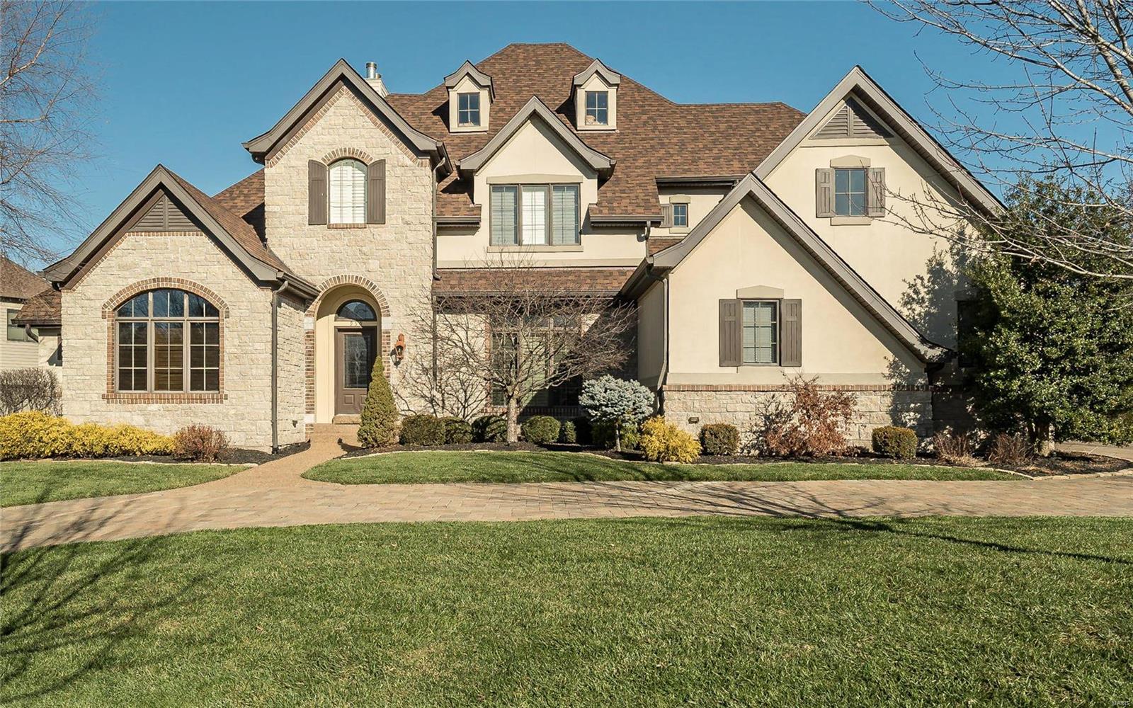 This dramatic 1.5 story Country French Oxford Plan Masterwork Series offers superb design and exquisite finishes throughout +6000 sq ft of finished living space. This Miceli built display home offers exceptional craftsmanship and custom millwork. The two story great room offers a fireplace, built in bookcases and wet bar that joins the large kitchen. A cooks dream kitchen includes an open floor plan, granite counters, stainless appliances, large pantry, custom cabinetry and breakfast room adjoining the beautiful hearth room. This lovely 4 bedroom, 4.5 bath home features a coffered ceiling in the master bedroom suite with a luxurious bath. The upstairs offers 3 bedrooms including a bedroom suite and loft area. The finished lower level offers a gas fireplace, wet bar, full bath, extra sleeping area and plenty of storage. The professionally landscaped yard is complete with a gorgeous salt water pool, covered patio and a hot tub that is perfect for family entertaining.