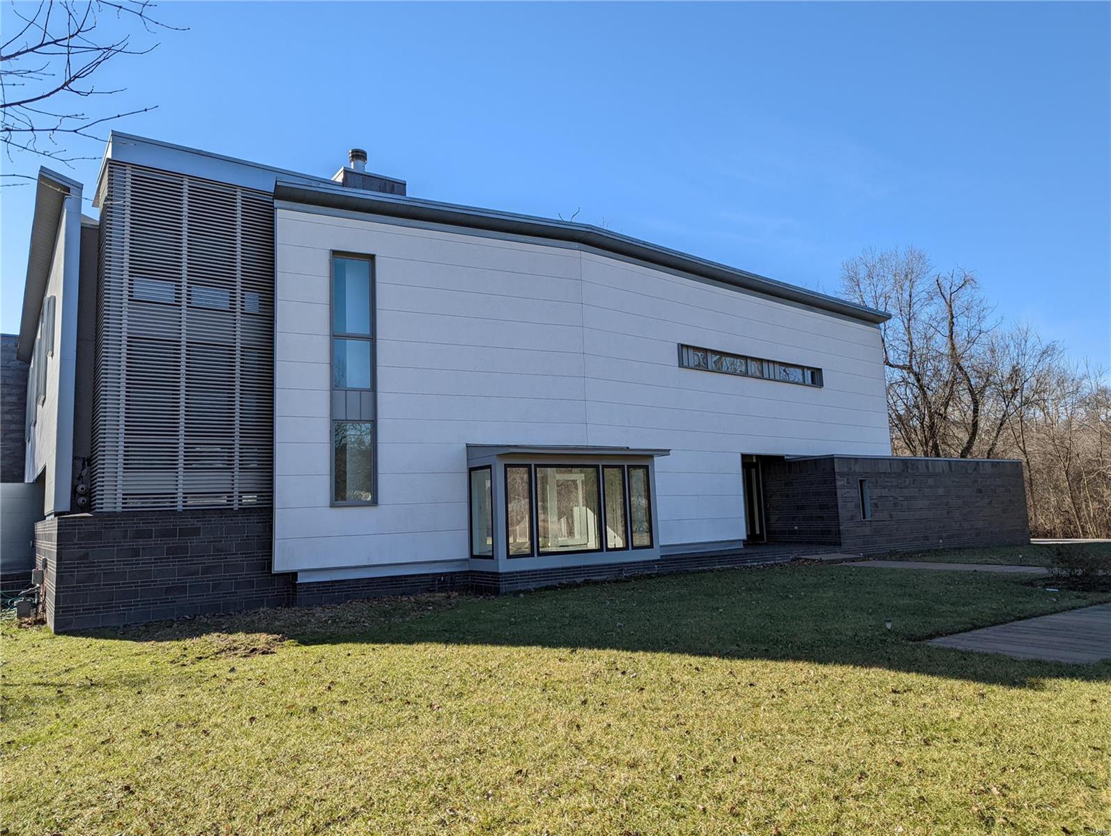 This custom designed contemporary home is a breathtaking and sophisticated work of art. Rising tall and sitting on 3.47 wooded acres, this home features open living spaces throughout. A wood burning fireplace is the centerpiece of the sprawling living room with an abundance of windows and doors offering amazing views of the back yard and patio areas. Step up into the stylish kitchen and dining area that leads to an office and another living area perfect for a family room or gym. Bedrooms are located on the 2nd floor as is the laundry room. The primary bedroom is loaded with closets and the bathroom has a jacuzzi tub, double sink vanity, and a separate shower. Walk out onto the roof and relax with amazing views of the back yard, woods, and tennis court. Additional living and storage space in the basement. Property is lender-owned, is being sold “as-is”, and seller makes no representations or warranties.