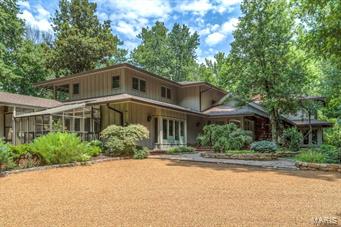 Spectacular 1.5 sty contemporary in premier Ladue location! Over 7400 sf of living space enhanced by gleaming wood floors, soaring ceilings, plantation shutters & art glass doors. Vaulted study with built-in bookcases leads to step-down living room with full-height fireplace & wet bar and spacious family room with brick fireplace & adjacent game room. State-of-the-art kitchen featuring custom cabinetry, granite countertops, professional quality appliances, center island with breakfast bar & butler’s pantry adjoins light-filled breakfast room & hearth room with wall of bookshelves & fireplace. Sumptuous master bedroom suite with 2 customized walk-in closets & lavish bath with steam shower & air tub.  Expansive solarium/workout room opens to pool area & greenhouse. The 2nd floor includes 4 additional bedroom suites (2 with balconies), sitting room & bonus room. Tucked away among 15 acres of secluded woods with private terraces, waterfall, woodland gardens, pool, hot tub & 3-car garage.