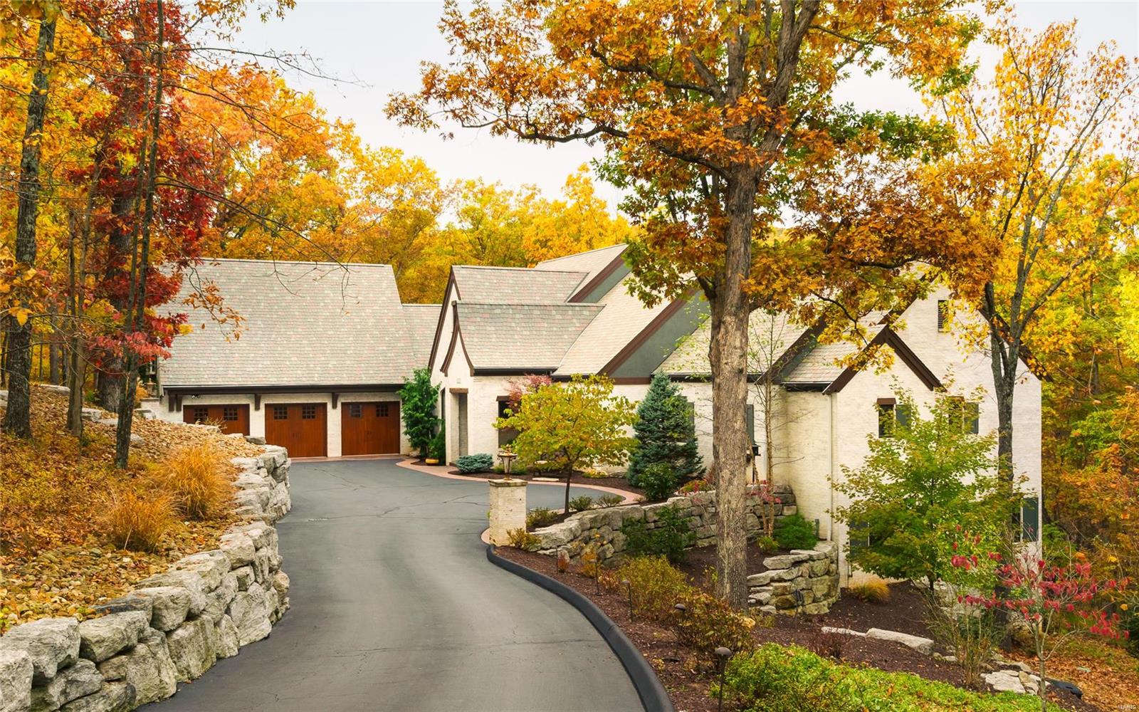 PLEASE NOTE - Home is in STL County - High Ridge P.O. only. This private retreat is nestled in 3 acres of wooded glory; masterfully designed for low maintenance with  old world charm. Modern luxuries fill the interior. 9’ to 14’ architectural ceilings, large leaded glass windows,  3 beautiful stone fireplaces resting on 1st floor Brazilian Mahogany or Italian PauLope wood on the expansive deck.  The main floor master bedroom is spacious. The spa-like bathroom features his/her  vanities, closets, water closets, pass through shower &. steam room.  The custom kitchen with burl wood accents & a large hidden pantry provide a warm atmosphere and a great  view of the outdoors. The Lower Level has a living room, two large bedrooms (not pictured), 1+ bathrooms, PLUS A 1,723 SF PARTIALLY FINISHED BONUS ROOM with walk out (not pictured). This unique space can be easily transformed to indulge any personal  preference. Oversized 3-car garage - large home generator. Home cost over $1.9M to build. Some Accessible Features