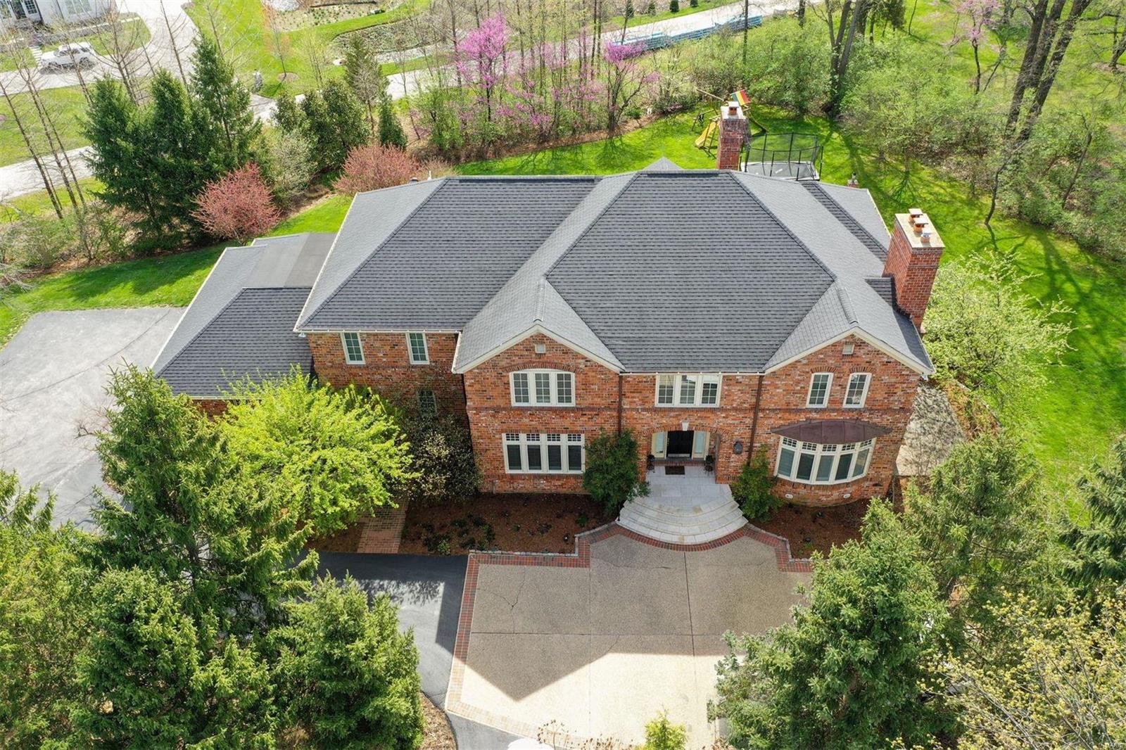 Elegance abounds in this glorious home on a private lane in the heart of Ladue! A sweeping staircase highlights the two-story entry. The serene living room with a gas fireplace leads to private patio. Enjoy the light-filled study with stunning built-in bookcases. The magnificent family room has a cathedral ceiling and grand fireplace. The kitchen includes a large island, Thermador 6 burner range, a wall oven, warming drawer, wine cooler, and walk-in pantry. Step outside to the expansive stone terraces and outdoor kitchen. The secluded second-floor main bedroom has a gas fireplace, luxurious bath with heated floors, soaking tub, steam shower, and his & hers closets. A back staircase leads to the lower level, which includes a play/exercise room, family room, kitchen, guest bedroom, bath, guest laundry, and a glass-doored wine cellar. French doors lead to the pretty pool and backyard waterfall. Geothermal, 3 zoned HVAC, and an oversized 3 car garage complete this dreamy home.