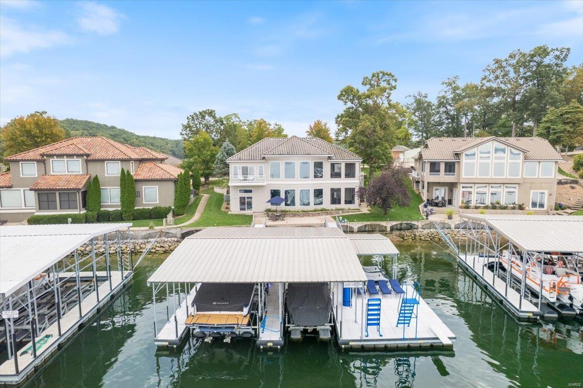 Lakefront Living at its finest. Coveted 10-Home Gated Community w/community pool in Molokai Pointe Estates in Sunrise Beach, MO on MM10! This 4-bed, 4.5 bath home is the Epitome of Luxury & Class! Features: Billionaire Views of the Main Channel thru a 25' wide wall of floor to ceiling windows, 12’ ceilings, 3-car garage, Flat driveway, Open floor plan, Chef’s dream kitchen w/ granite countertops, huge bar level island, +60" fridge/freezer, walk-in pantry, 2 walk-out covered patio, Main level master suite w/steam shower, large walk-in closet w/laundry, & private deck w/lake views, wet bar w/ice maker & kegerator, game room & family room, 3 more ensuite bedrooms w/ 2 having private view/private water access, laundry room. Walk-out just 15' from seawall to a double walkway onto a 3 Well dock (14x36, 10x26, 12x12) w/double pwc hoist, wet steps, high dive, & diving board. Enjoy the big main channel views & calm water thanks to a community breakwater. Turnkey property! Additional Rooms: Sun Room