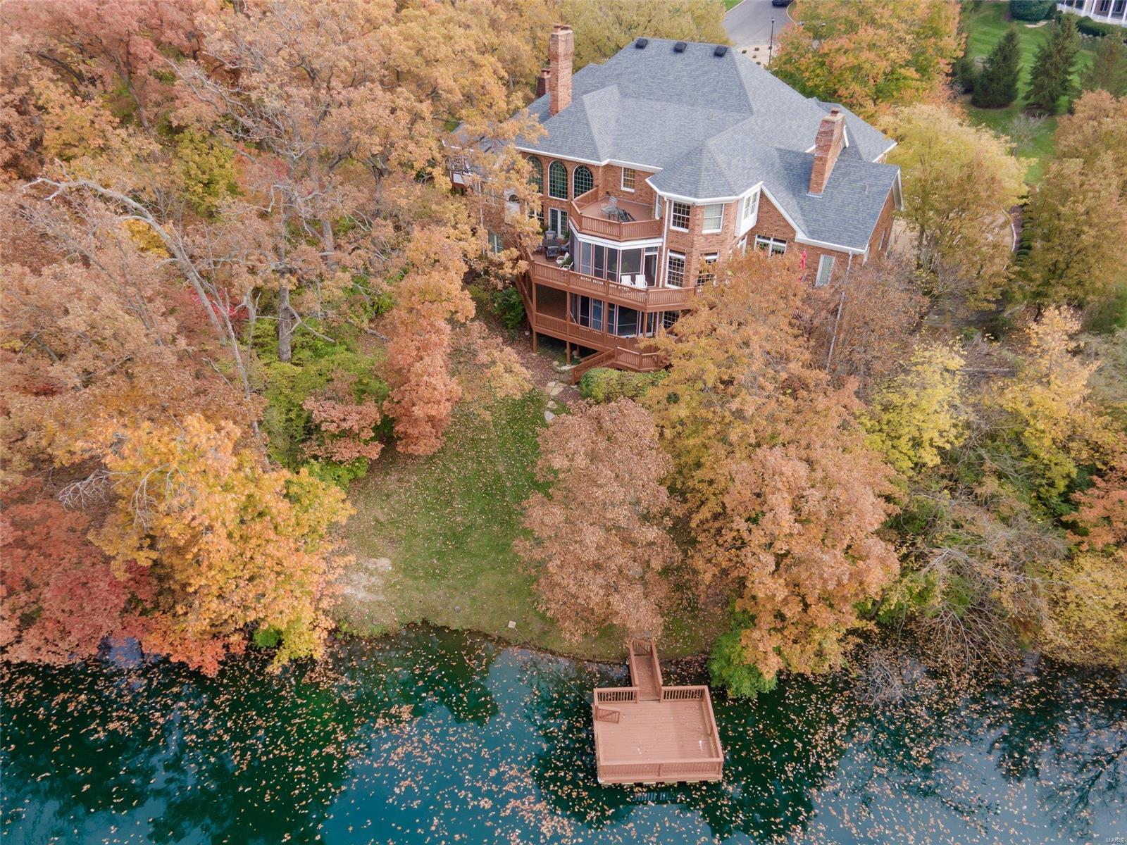 Stately Town and Country home on private 2.5+ acres! Nestled among trees with incredible views of private stocked lake complete with dock. Full Brick construction. Multi-zone geothermal heating and cooling! LOW UTILITIES! 2-story entry w/ turned staircase. Grand 2 story living room, fireplace, book shelves, wetbar, and balconies. Cozy wood paneled den/office with built-in bookcases and fireplace.  Master Bedroom suite includes private 3 seasons room! Do you like to entertain? This home is a dream for hosting small to large gatherings.  The Kitchen/Breakfast/Heathroom (which opens to deck and screened porch) is perfect for hosting family & friends!   2nd floor has 3 bedrooms & sitting room.   Lower level is perfect for in-law/guest suite and includes kitchen, 1+ bedroom, 3 baths, media room, game room, gym & family room with fireplace & private screened porch. Elevator service to all 3 levels.   Incredible Millwork & construction!  4car gar w/ EV charging. Plenty of extra parking space. Some Accessible Features
