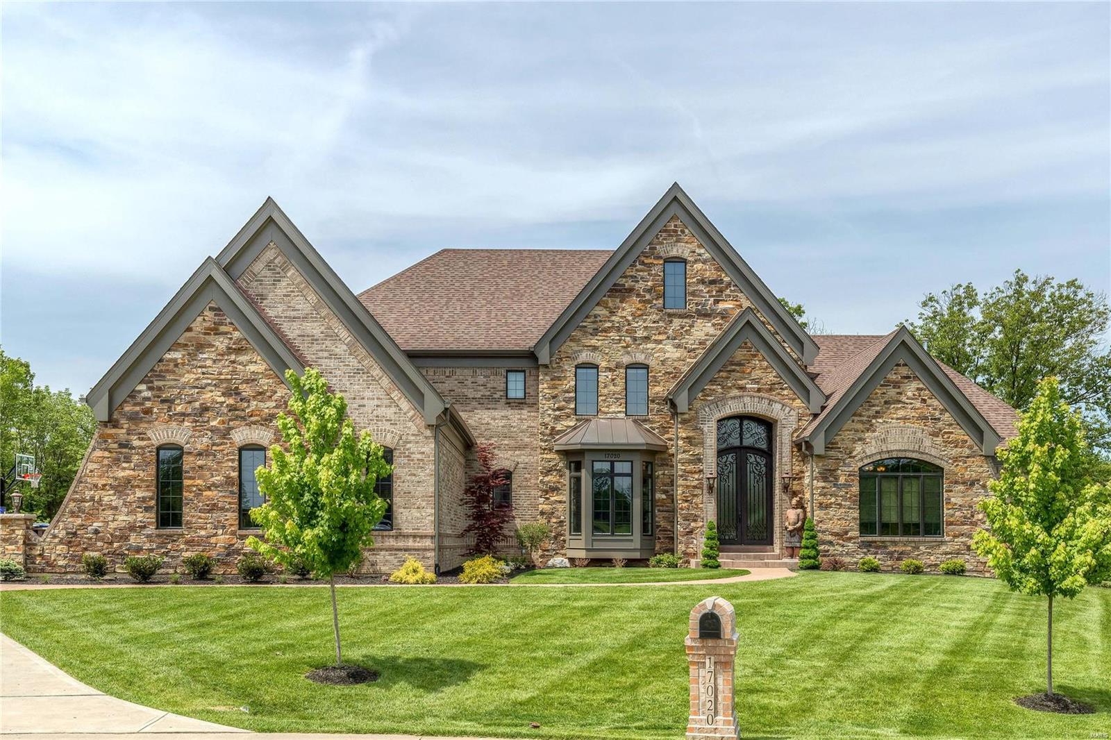 Spectacular brick & stone Estate home on 3-acre grounds! This Byrne-built 1.5 Sty features extensive millwork, 10’ ceilings, oak hardwoods & integrated sound system. Extraordinary iron double doors open to 2-sty foyer, library-paneled study with built-in bookcases, elegant dining room & stunning great room with beamed ceiling, full-height stone fireplace & dramatic wall of windows. Chef’s kitchen with 42” glazed cabinetry, granite countertops & premium appliances adjoins breakfast room with convenient planning center, gathering room with entertainment center & screened porch highlighted by stone fireplace. Coffered master bedroom suite with wide bay window & luxury bath with jetted tub offers an appealing retreat. Front & rear staircases access 4 additional bedrooms, 2 with ensuite baths & 2 with Jack n’ Jill bath, plus 2nd floor laundry. Lower Level includes recreation room, wet bar, family room with fireplace, office & full bath. Private cul-de-sac lot with 2 patios & 4-car garage. Additional Rooms: Mud Room