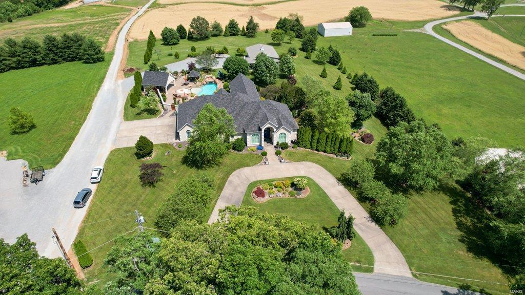 Upscale estate built on 2.82 gorgeous, extremely well manicured acres right outside the city limits. Beautiful hardwood floors span throughout the main level. Kitchen features custom cabinets, SS appliances, eat-in breakfast area & a pass through to the formal dining room. The main level master suite has a spacious en-suite with his/her walk-in closets/sinks and separate whirlpool tub & walk-in tiled shower. Step outside from the large 4 season family room to your own private backyard paradise which boasts a self-cleaning, beach-entry pool with waterfall & grotto, pool house with bathroom an attached green house and an outdoor kitchen and bar. Other highlights include a 35x45 detached garage, greenhouse, full irrigation system, theater room and lower level wet bar.