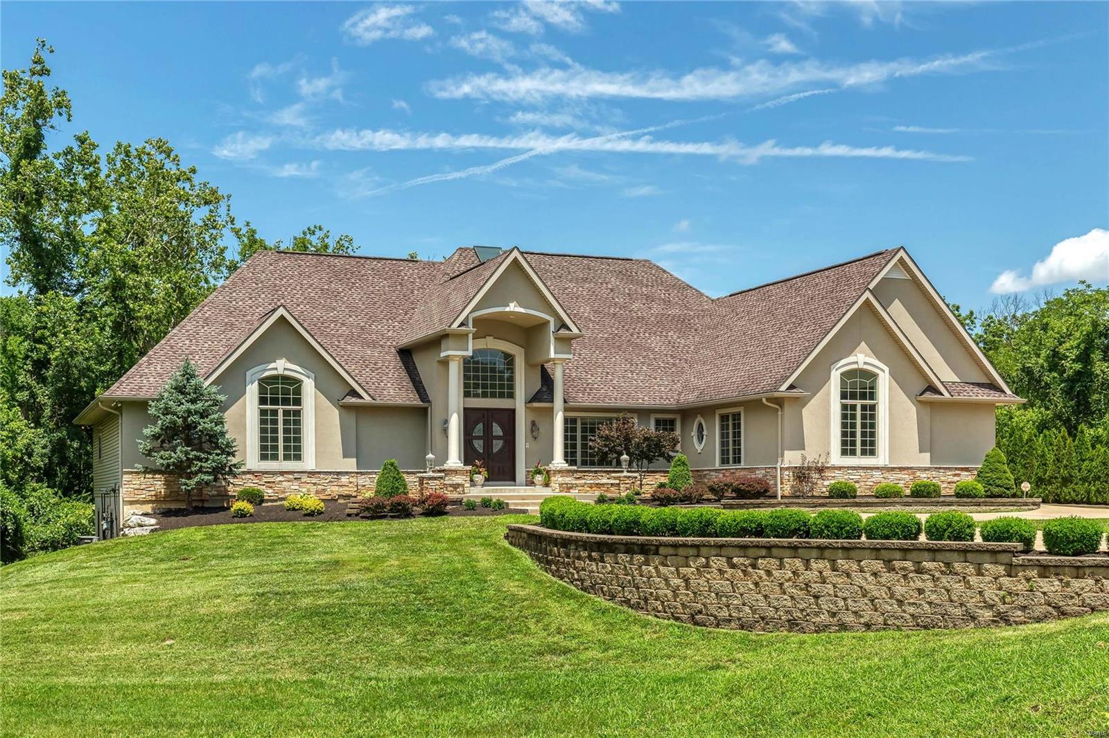 Prominently situated at the end of the cul-de-sac, this custom-built ranch home with its impeccable landscaping & 2-sty porch entrance with 8’ mahogany double doors makes a stunning entrance. Grand 2-sty foyer with gallery staircase opens to sophisticated dining room with architectural column & coffered great room with cast stone fireplace & dramatic wall of windows. Designer kitchen with glazed buff cabinetry, granite countertops, premium appliances & 8’ center island adjoins breakfast room with sliding glass door to deck & vaulted hearth room with wide bow window & fireplace flanked by display cases. Sumptuous master bedroom suite with His & Hers walk-in closets, sitting room & luxury bath with shower spa & Jacuzzi plus 3 additional ensuite bedrooms complete the main floor living quarters. Lower Level includes expansive recreation room with wet bar, media room, office, workout room & 2 guest suites. Situated on 1+ acre grounds with patio, circular drive with fountain & 4-car garage.
