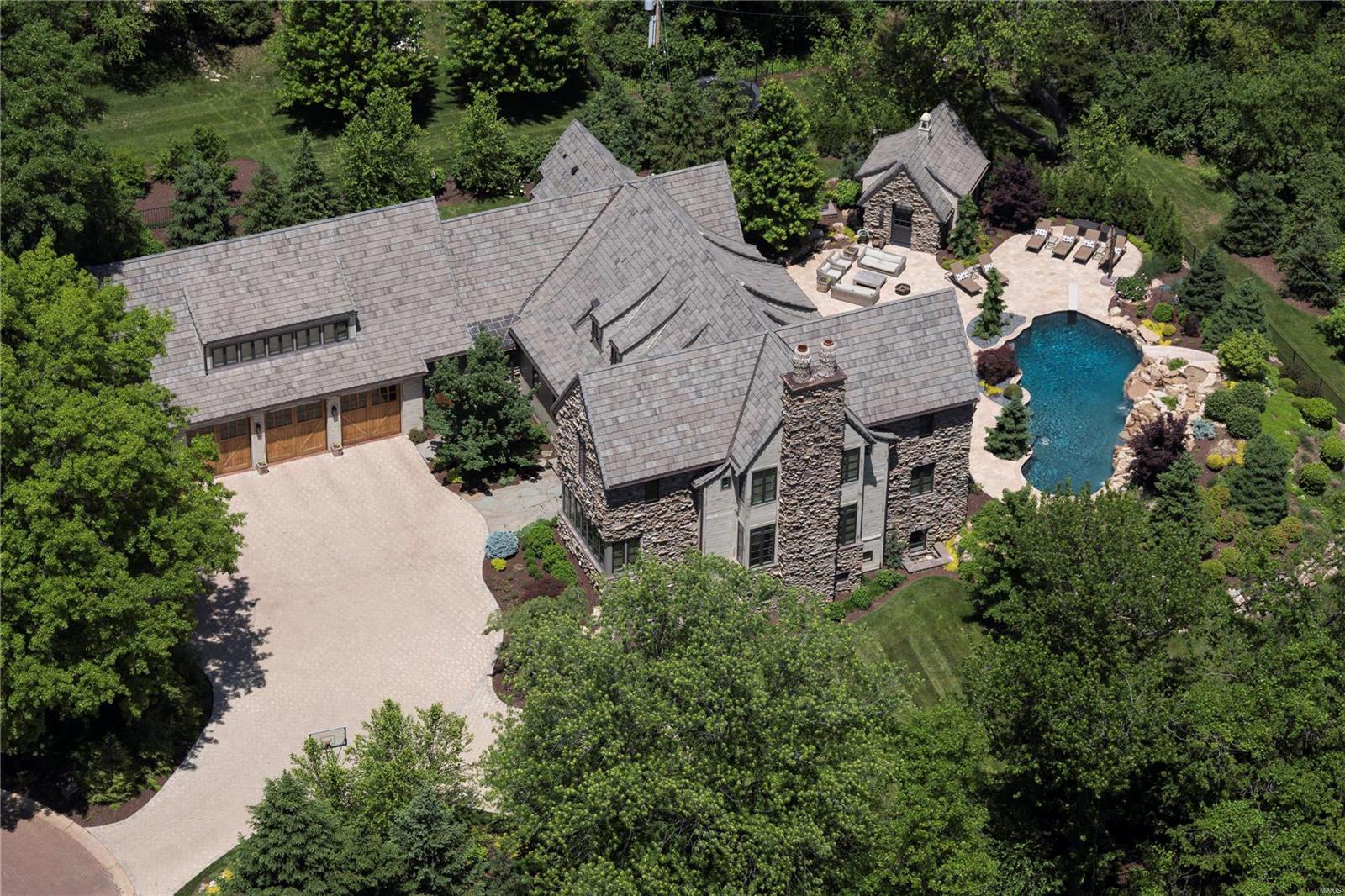 Significant price adjustment creates best overall value for this World Class property of singular design. This 3 year old home in Town and Country's best location, was selected by Architectural Digest as one of Saint Louis' most distinctive properties. Nationally acclaimed McAlpine architects created this custom English Country Manor home of 6,900 square feet, with five bedrooms and Guest Quarters. Exteriors of weathered fieldstone and Missouri walnut highlight the curved Stoneworth roofline in concrete shingles. 26 tons of geothermal heating/cooling and a whole-house generator servicing the home. A Baker free form pool showcases natural looking waterfalls. Wide plank ash floors are radiantly heated. Bedrooms are all en-suite, with heated floors and walk-in closets. 100-year old Missouri barn wood, throughout. Chef kitchen hosts two walk-in pantries for food prep. Deep pour Lower Level offers billiards, full gym and office. Walk to Straub's and the new Town and Country Center.