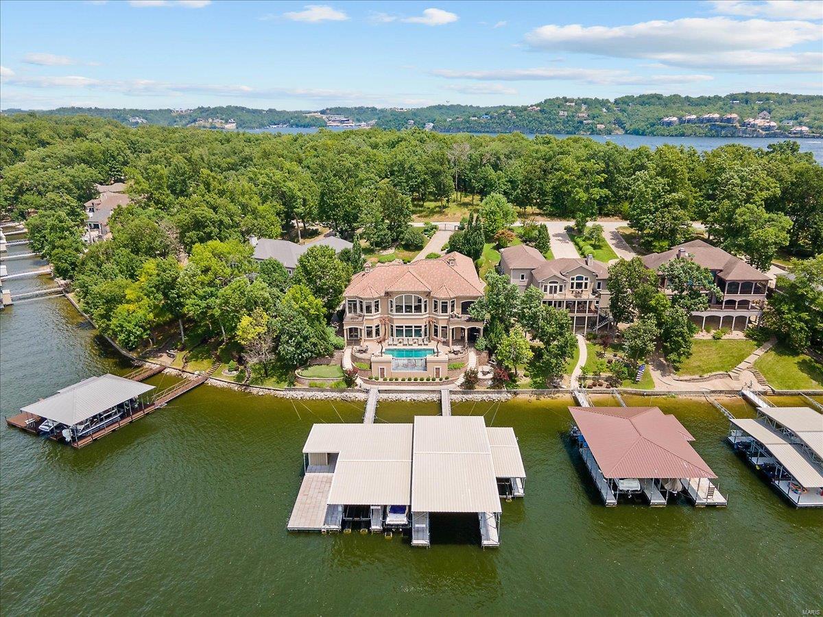Luxurious Porto Cima Gated Lake Home with exquisite details, furnishings, patios, heated pool, putting green now embraces a totally renovated exterior of stucco & all the details. Grand front entrance of massive open spaces with 14 - 17 foot ceilings high grade features including spacious, beautifully detailed entertaining areas inside & out that will be sure to please you & your guest. Travertine floors, extensive millwork, custom tilework in baths, five suites, gourmet kitchen, lower level kitchen, a master en suite spa, 2 laundry rooms plus stack washer/dryer in Master. Upgraded & impressive infinity edge pool surrounded by stamped concrete and a wonderful outdoor fireplace, upstairs screened deck, bbq area and bar with minimal steps to the dock. Dock will more than accommodate your needs with four slips of various sizes (largest is 20 x 60), a bar/locker storage & large swim platform