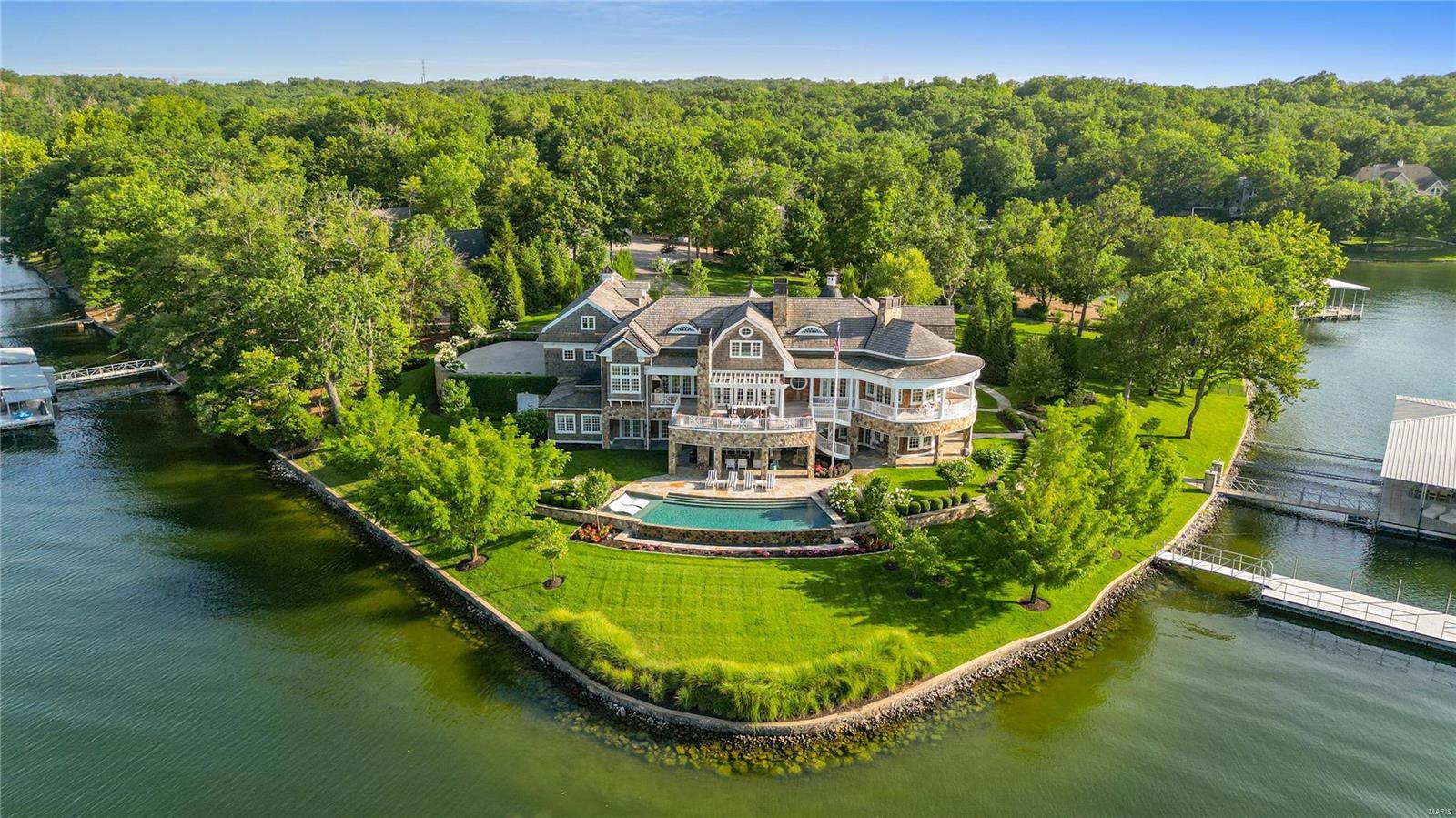 Nantucket Point is without a doubt the crown jewel of the Lake and sits on a one-of-a-kind 1.24 acre point with 500’ of shoreline w/seawall, deep water and views of main channel, while cove protected. 6,800+ sf Nantucket-inspired estate is filled with laid-back luxury, coastal design and hidden passageways leading to tucked-away space. Every room has a view of lush landscaping and sparkling lake. No attention to detail spared – cedar shingles, shiplap construction, board & batten hallways, unique lighting and fixtures at every turn. Open living area w/stone fplc, 6 ensuites incl 2 bunk rooms, 2 half bath, 2 gourmet kitchens, office, den w/fplc, gym, game room and more. 3,100+ sf outdoor living space – covered patio, wraparound deck and veranda w/fplc. Infinity pool is steps away from the lake and 2 docks – one w/2 slips, jet ski lifts and kitchenette/one wave-break w/high dive and slide). 3-car garage. TURNKEY HGTV award-winning lakefront home – a rare opportunity to enjoy on day one.