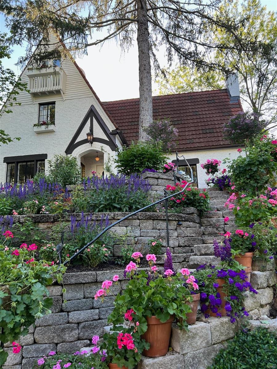 Charm and sophistication abound in this remarkable English-style cottage tucked away on a quiet lane in the heart of Webster Groves.  Remarkable architectural features include a soaring vaulted living room ceiling accentuated by hand-hewn beams, a large arched fireplace with a two-story chimney breast, beamed ceilings in the dining room, kitchen, and primary bedroom, original casement windows, and outstanding treillage wall detailing in the family room with its built-in bar. The charming updated kitchen is truly one-of-a-kind with amazing attention to detail throughout. The second floor includes a guest bedroom, bath, and primary bedroom which leads to a full third-floor dressing room and updated bathroom.  The rear garden offers the perfect outdoor entertaining space with its unique dipping pool, and waterfall leading to a beautiful koi pond.  This home is a rare gem conveniently located near shops and restaurants in downtown Webster Groves.