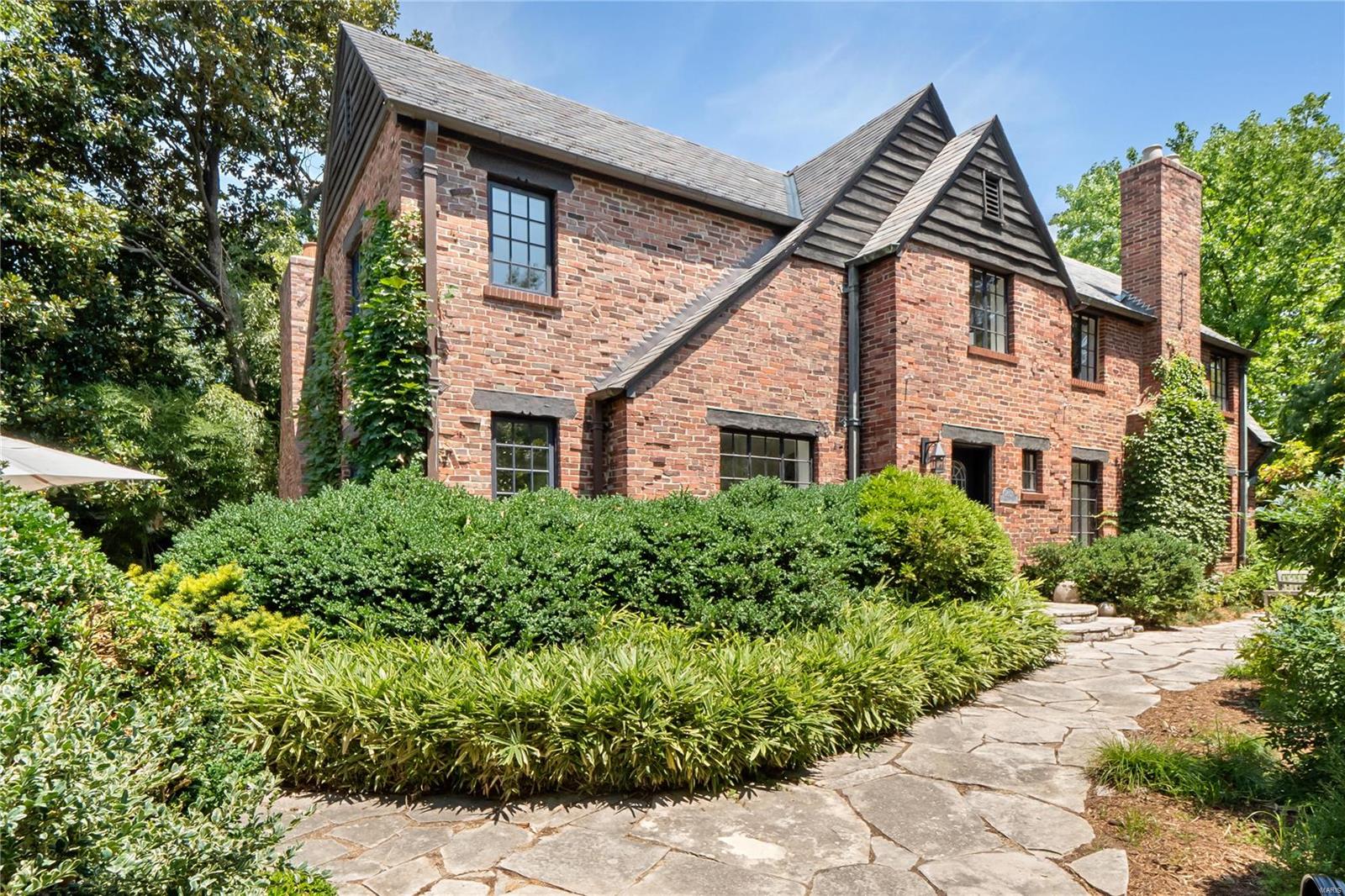 This stunning Tudor home, located in Wydown Forest, has been tastefully expanded and completely renovated to exemplify luxury living. The lush green landscape design provides complete privacy. The home has beautiful oak flooring throughout & an elevator that services all floors. The kitchen features granite counters, center island & high-end appliances. Off the kitchen is a cozy hearth room with a gas fireplace. The main level also has a family room, large dining room and a living room with a fireplace and built-ins. Impressive 2nd floor primary suite with ample closets and a marble clad bath boasting an oversized shower and vanity with dual sinks. Three more bedrooms and a full bath complete the 2nd floor. The lower level has a butler’s pantry with a wine fridge, refrigerator and ice maker.  The flagstone patio wraps around the entire house and features a grand wood-burning fireplace & multiple areas for entertaining. Geothermal heating & cooling. 2-car garage.