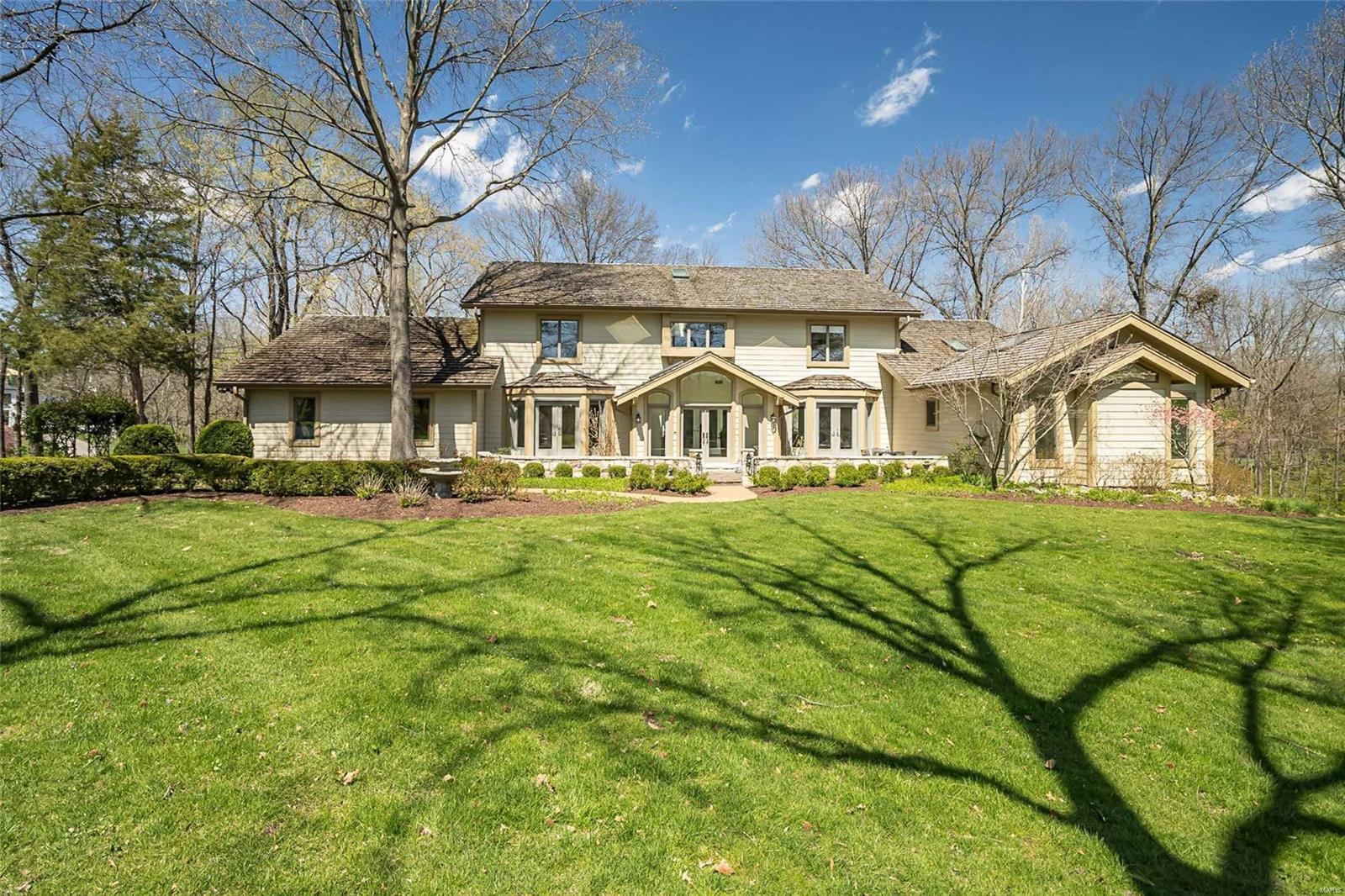 Situated on top of a hill on a very private 2.548 acre lot with beautiful views, this charming 1.5 story one owner home has been expanded to create a floor plan with today’s lifestyle in mind. This 5 bedroom, 5.5 bath home offers a light filled great room, a tranquil study and formal dining room with butlers pantry. The well-equipped kitchen with center island opens to expansive hearth room/breakfast room with stone fireplace, vaulted ceiling and woodland views from every window.  Main floor primary suite has a sitting room, walk in closet and spacious bath. The gracious staircase leads to an upstairs landing with bookcases, 3 bedrooms and 2 full baths. The walk-out LL has a guest suite with private entrance, lovely bath and stone fireplace. The lower level boasts two family rooms, one with fireplace, another full bath, kitchenette, laundry and terrific storage and closets. Main floor laundry, 3 car oversized garage, irrigation system. All within walking distance to Old Warson CC!