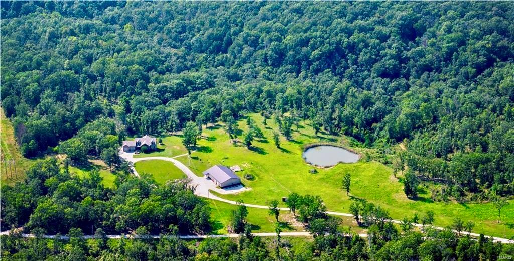Experience tranquility on this extraordinary 32-acre estate featuring a beautiful pond, a 3,800 sq ft two-story shop, and ultimate privacy. This custom-built home offers 7 bedrooms, including 3 master suites, an open floor plan, and a chef’s kitchen. The all-steel shop includes a full apartment, while the property also boasts a media room, workout room, office, and more. Ideal for livestock and gardening, this move-in-ready property combines luxury and country living, with easy access to Highway 54 and Lake of the Ozarks.