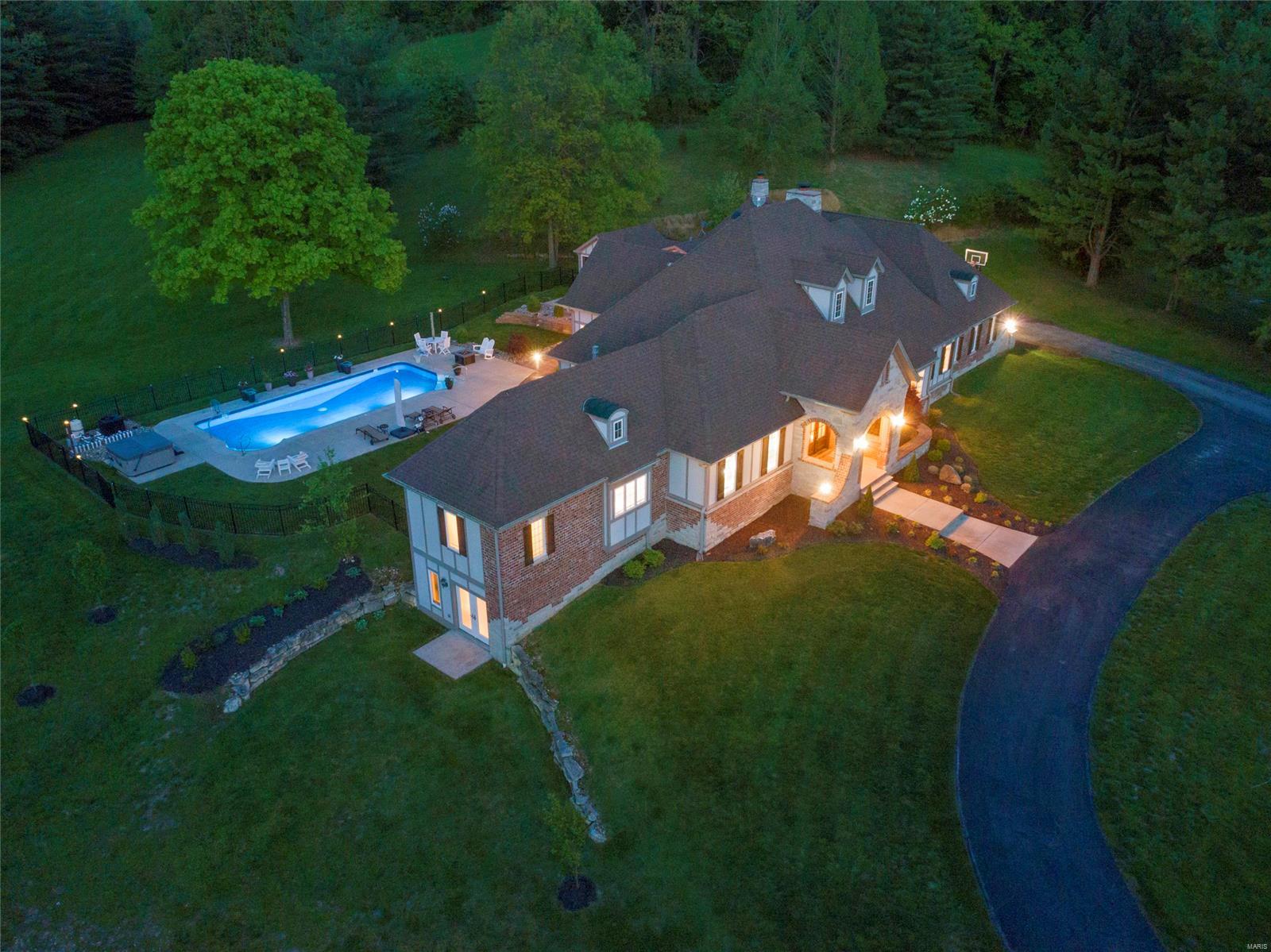Wildwood, Rockwood Schools; Prestigious, custom built ranch ranch nestled on 9.8 level acres with stunning outdoor living area including 2 yr old pool, hottub, pool house & private bath. Ideal horse property!. The brick/stone elevation is accentuated by the arched double-door entry welcoming you to enjoy wide-plank, hand-scraped hdwd floors throughout the main floor. Features include tray ceilings, dramatic vaults, crown, built-ins & 2-panel 8ft doors. A grand center island is the highlight of the kitchen which includes top-of-the-line appliances, custom cabinetry, granite counters, tile backsplash & opens to the hearth rm w/floor-to-ceiling stone fireplace. Master suite boasts a deep coffered ceiling, master bath w/his-n-hers vanities, walk-in shower & custom walk-in closet and french doors leading to the private screed porch. Three BRs, one w/fireplace, & 2 full baths create the add’l bedrm wing. Finished walk-out lower level with bedrm, full bath, entertainment area & exercise rm.