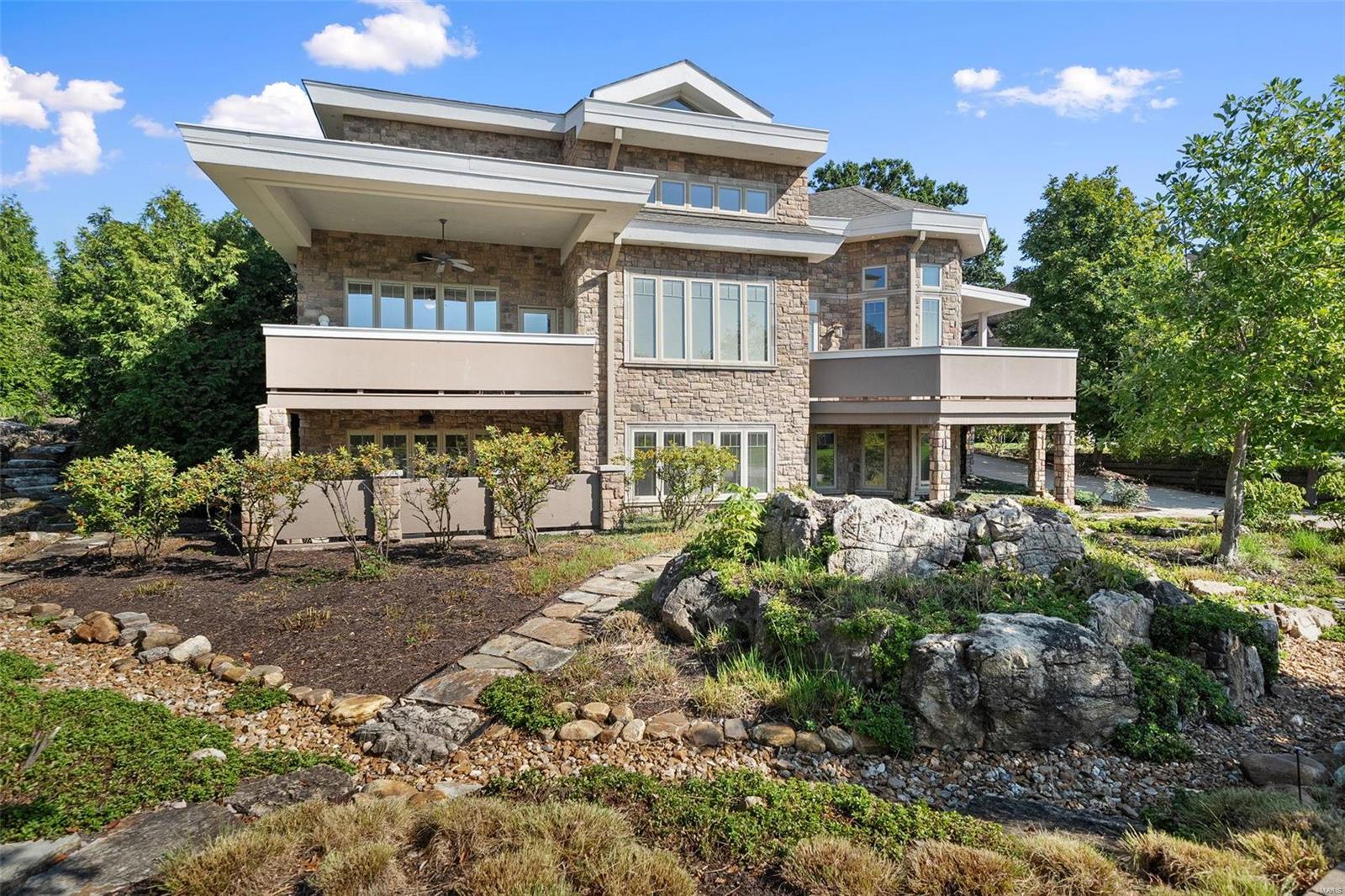 This impressive home is nestled an upscale neighborhood. Immediately you will notice the water feature and beautiful gardens (trimmed back for the Fall) & balconies creating remarkable outdoor living. A beautiful foyer welcomes you, an office to your right with a full bath, a great 4th bedroom option. To the left a convenient open floor plan. The dreamy kitchen offers custom cabinetry, stone countertops, high-end appliances & both counter seating & an eat-in table. The kitchen is open to the dining room, family room & living room, great for entertaining! Doors off these rooms lead to an unbelievable patio with a Wolf grill & plenty of areas to enjoy the views. Also on the main floor the spacious primary suite with a pleasing bath, generous closet, & patio. Downstairs is an expansive recreation room offering a bar/kitchen, a second powder room, 2 great sized bedrooms with walk-in closets & full baths. Additionally this home offers a gym space, 3 car garage and main floor laundry.