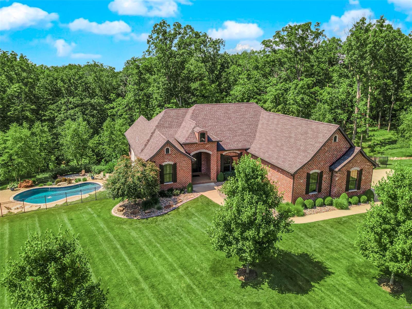 Custom Craftsman Ranch with 4,200 sq ft on 3-acres with mature trees and impeccable landscaping, in ground Gunite pool, hot tub, composite decking & covered deck. There are neighborhood lakes for kayaking & fishing too! The main floor is covered with engineered wide plank hand scraped European white oak flooring. Kitchen includes a built-in Viking refrigerator, large center island breakfast bar with granite counters, under and upper cabinet lighting, a farm sink and subway tile. Split bedroom floor plan with Jack-n-Jill bath and a guest bathroom. All of the bedrooms have plantation shutters and attached En suites! Primary Suite includes atrium doors to the deck, walk-in custom dressing room with granite island, tub & shower and two sinks. Formal dining room with granite serving and wine bar. Coffered ceilings in the great room with gas FP.  Deep Pour w/out LL with in-law suite and second kitchen/bar area. Insulated 3-Car Garage with 8 foot doors is 25x27 and 12x20 with Pro Slat wall.