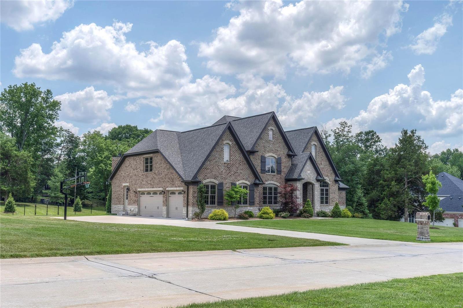 This 1.5-sty Estate home redefines luxury living! Over 6600 sf of living space w/ soaring ceilings, elaborate millwork & wide plank flooring on the main floor. Extraordinary 8’ wrought iron double doors lead to grand 2-sty foyer, paneled study w/ vaulted ceiling, elegant dining rm & stunning great rm w/ fireplace with cast stone mantle & dramatic wall of windows. State-of-the-art kitchen with 42” white cabinetry, granite countertops, Thermador appliances, 9’x7’ center island with walnut butcher block top & butler’s pantry adjoins breakfast room w/ bay window & hearth room highlighted by floor-to-ceiling stone fireplace. Coffered master bedroom has 2 walk-in closets & marble bath. Hardwood staircase accesses 3 bedrooms, 1 with ensuite bath & 2 with Jack n’ Jill bath & a raised media room. Walk-out LL has rec room, billiard room w/ stone fireplace, 2nd kitchen, office, 5th bedroom & full bath. Professionally landscaped 1.66 ac grounds with award winning designed pool & 3-car garage.
