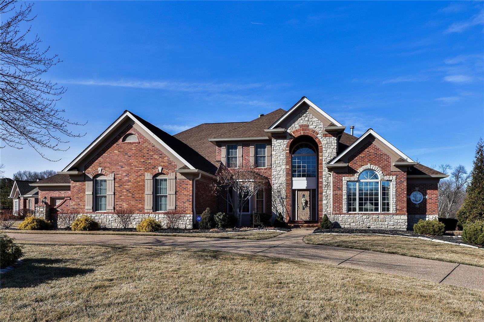 Discover luxury living in this exquisite 1.5-story stunning brick & stone front. Circle exposed aggregate driveway. Complimented by two story entry & T-staircase.  Step into elegance with main floor master suite, box window with window seat with cedar storage. Gorgeous master bath with adult separate vanities including nice make-up area. Built-in bookshelves adorn the space. Two story great room with see through fireplace. Wood floors on most of the main level.  Kitchen with granite counters, newer double oven and raised breakfast bar all open to breakfast room and hearth room elevate the kitchen's appeal. Dive into relaxation in the serene inground pool or entertain in the finished walkout lower level. 3-zone heating/AC, 2 hot water heaters, integrated speakers throughout.  4 car drywalled garage.  You'll love the professionally finished lower level with two different walk outs. Great storage for pool stuff. This home is a masterpiece of comfort and sophistication.