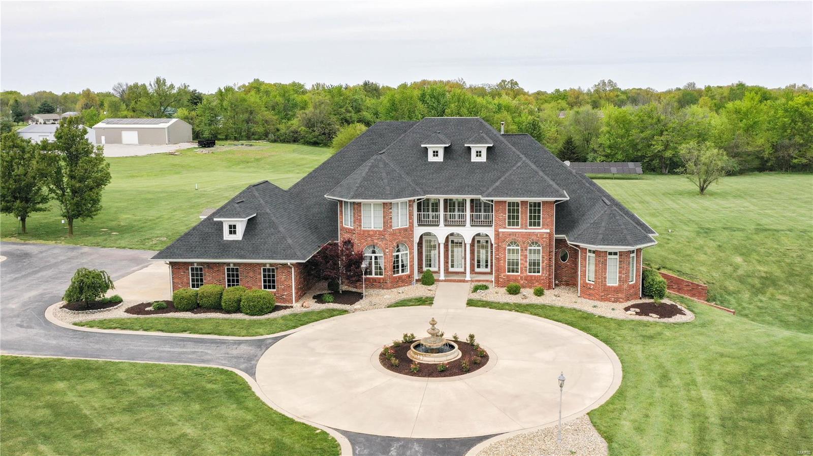 Car enthusiasts dream property! This beautiful estate is situated on nearly 10 acres in Brighton, IL and less than 5 minutes from interstate 255. It boasts a nearly 7,200 sq ft home and a massive 3,400 sq ft, insulated and climate-controlled metal outbuilding complete with concrete floors, extra storage, finished office space, and a bathroom. This space could have commercial and/or storage possibilities with high visibility. The all-brick home features 4 bedrooms, 5 bathrooms, an elevator to all floors and a stunning great room with a catwalk and gas fireplace. Gourmet kitchen with Viking appliances, granite counters, and heated floors. Expansive master suite. Heated in-ground pool with hot tub and cool deck patio. Attached 3-car garage with heated floors, ready for your EV charger. Finished walkout lower level with kitchenette and theater room. Geothermal HVAC, central vac and a whole-house sound sys. Luxurious living awaits in this exceptional property. Schedule your viewing today.