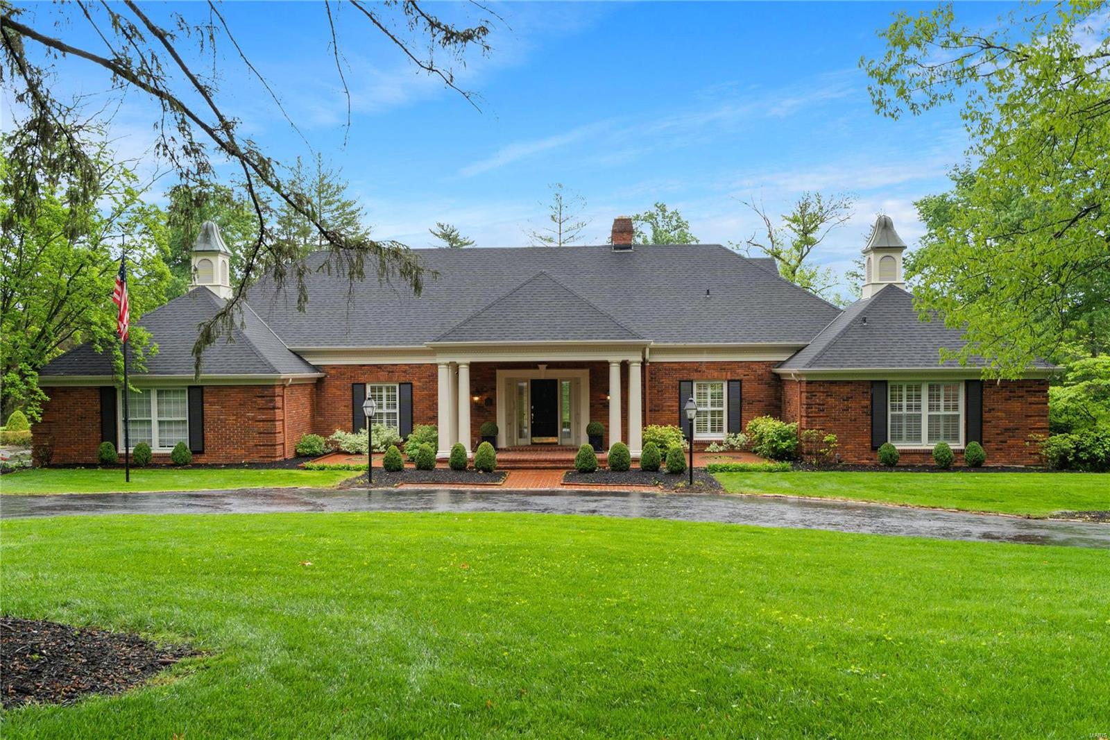 Presenting a distinguished story-and-a-half home situated in the stunning Bellerive Country Club Grounds. This light-filled residence boasts living spaces on the main level with expansive windows that frame views of lush backyard and brick patios, perfect for large gatherings. Designed for entertaining, the home offers seamless flow throughout. The den, complete with a fireplace and hearth, built-in wet bar, and bookshelves, provides a cozy retreat while the formal living room invites conversation and opens to the dining room. The eat-in kitchen has stainless steel appliances, quartz countertops, and an adjacent laundry/mudroom. A spacious main-floor primary suite features abundant closets and a renovated ensuite bathroom. Adjacent to the primary suite is a 5th bedroom or office. Upstairs are three bedrooms with custom closets and a bath with a double sink vanity. The finished lower level comprises a kitchenette, a full bath, and storage. Three-car garage, circle drive, and irrigation. Additional Rooms: Mud Room