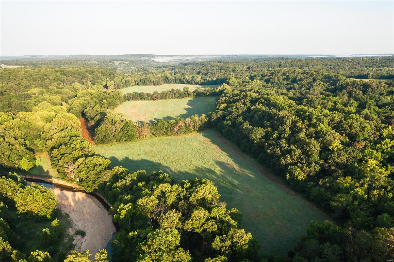 Broken Arrow Ranch is the epitome of a true hunting destination. 443 +/- acres loaded with large numbers of deer and turkey. With 85+/- acres of open and 55 acres of fertile bottom fields converted back to row crop. The very impressive and vast Oak and Walnut timber throughout the property has been valued at well over $200,000 with full appraisal in process. Atwell creek meanders through the center of the property. The 3 bed, 2.5 bath lodge has many recent updates, two large fireplaces, and stunning views overlooking the big bottom fields and creek. As many as 33 deer and many more turkey have been viewed from the sun porch at one time and wildlife in the yard is a common occurrence. Five outbuildings consist of two large hay barns, implement shed, smoke house and horse barn with three horse stalls. 60 fertile acres are currently leased for row crop with the remainder in established food plots and bedding. Three new Banks Stump hunting blinds included with the sale.