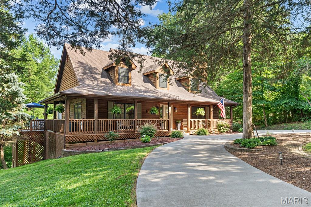 Welcome to 340 Great Oaks Drive, an extraordinary wooded retreat where timeless craftsmanship, natural beauty, and modern comfort come together in one remarkable property. Nestled among towering mature trees on a beautifully landscaped lot, this meticulously maintained home offers the privacy and serenity of a country escape while remaining conveniently located near everyday amenities, including highly regarded Labadie Elementary School.

From the moment you arrive, the inviting wraparound front porch creates a lasting first impression. Whether you're enjoying a peaceful morning coffee, hosting friends and family, or unwinding after a long day, this expansive outdoor living space provides the perfect setting to relax and take in the picturesque surroundings.

Inside, you'll find three spacious bedrooms and two and a half bathrooms thoughtfully designed to support both comfortable everyday living and effortless entertaining. Soaring vaulted ceilings create an impressive sense of openness, while the stunning fireplace serves as the centerpiece of the main living area, adding warmth, character, and a cozy gathering place during every season. Rich architectural details, warm wood finishes, and scenic views throughout the home create a distinctive lodge-inspired atmosphere that feels both welcoming and refined. Large gathering spaces offer flexibility for family life, while the home's unique craftsmanship and timeless design set it apart from ordinary properties.

The walkout lower level expands the home's living and entertaining possibilities, offering seamless access to the outdoors and additional space for recreation, guests, a home office, or relaxation. The oversized driveway and attached garage provide ample parking and storage, while the beautifully maintained grounds reflect exceptional pride of ownership. Don't forget about the local path down the hill that leads to downtown Labadie; used recreationally via walking, biking, and for golf cart rides. Every detail has been carefully cared for, allowing the next owner to move in and immediately enjoy all this property has to offer.

Rarely does a home combine this level of privacy, charm, functionality, and location. Whether you're searching for a peaceful full-time residence, a place to raise a family near one of the area's most desirable elementary schools, or a tranquil retreat surrounded by nature, 340 Great Oaks Drive delivers an exceptional lifestyle in a truly unforgettable setting. Schedule your private showing today and experience firsthand the warmth, beauty, and character that make this property feel like home.