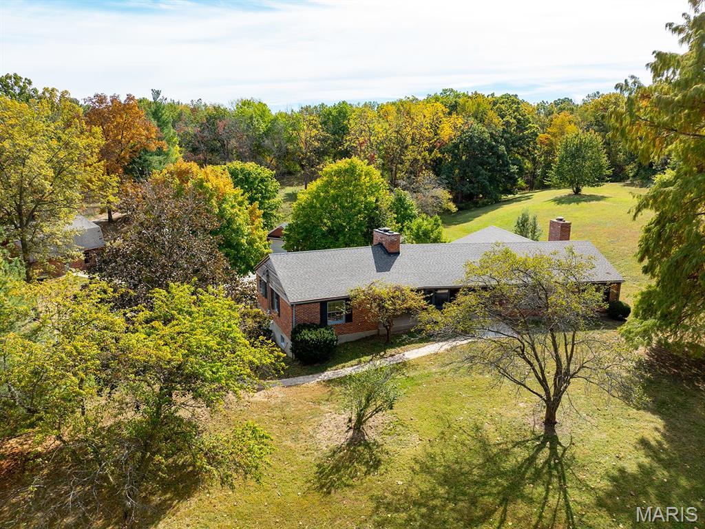 Almost unbelievable! A hidden gem with surveyed 13.387 acres within the city of Hannibal! Included is the approx. 2600 sq. ft. brick raised ranch style home, a 35'x25' outbuilding, a 2-car tuck under garage plus a 1-car detached garage, & peaceful "country" tranquility... in town! The old barn previously was home to a couple of horses. Here's a few other details: Quality steel beam construction! 3 spacious bedrooms & 2 full baths. Beautiful crown molding, radiant heated floors, massive closet space including an entire row of closets along hallway, & 2 fireplaces that add to the ambience. Expansive covered porch is access to the beautiful front entry foyer that extends through the home to the back patio. This private patio & the massive living room w/wall of windows both offer wonderful views of the wooded acres sheltering deer as they romp & play. If desired, Buyer could add a driveway to front entrance for any guests that need to avoid steps! (Occasionally, Seller has driven to the front as if a circular driveway existed.) The outbuilding with loft for storage offers the perfect place to enjoy your hobbies, park more vehicles, and/or store your grown-up style toys! Walking bridge leads to Gazebo for a different place to relax. This one-owner home was built by well-known and respected contractor, Wallace Smashey, who lovingly built this home for his family. Now it is available to be YOUR oasis and forever home!