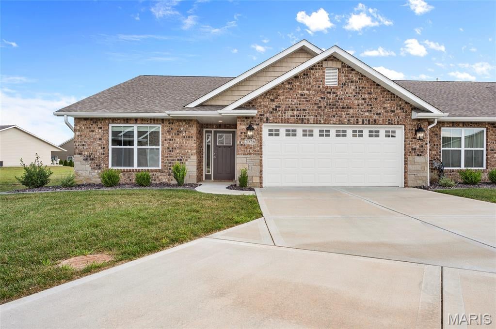 Welcome to this beautiful ranch home in Serenade Villas! Less than three years old, this 3-bedroom, 2-bath home offers modern finishes, an open floor plan, and convenient one-level living. The brick and stone exterior add curb appeal. Inside, the spacious main living area features vaulted ceilings and a gas fireplace with a shiplap surround, creating a warm focal point in the living room. The kitchen overlooks the living room and includes a center island, ample cabinetry, and stainless-steel appliances. The sliding glass door in the dining area opens to a covered porch, providing an inviting space to enjoy your morning coffee or relax outdoors. The primary suite has a private ensuite bath with a walk-in shower and dual vanities, along with a spacious walk-in closet. Located in a 55+ community, this home combines newer construction with comfortable, low-maintenance living. Some photos have been virtually staged.