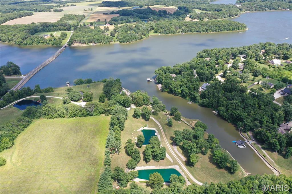Looking to build your own personal lake resort or divide the property for multiple home sites? Look no further than this one of a kind nearly 8 acre, waterfront property, just 1hr from St. Louis. Everything is ready to begin your dream lakefront home on this 1,200 acre lake. Enter your own security gate to your private oasis drive, lined with beautiful oak trees & vista views of Lake Glen Shoals. The property has 2 stocked ponds w/ colorful, large Japanese Koi, a one-of-a-kind gazebo shipped from Italy, & your very own lakeside sand volleyball court, complete w/ a drainage system. The road, water, electric, fiber optic cable, & septic system have already been installed. The lakefront has already been lined w/ keystone & rip rap & the cove has been dredged. Plus, enjoy the large inground swimming pool, hot tub w/ another Italian gazebo & firepit. This exquisite property also includes a boat dock w/ lift & 4 wave runner ramps. Priced for a quick sale w/ over $1.2 million invested.