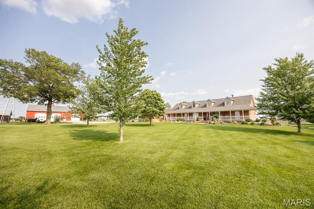 We are pleased to present an extraordinary opportunity to own a stunning 5-acre estate located within the highly sought-after Mascoutah School District.
This impressive atrium ranch home features 5 spacious bedrooms and 3.5 bathrooms. A grand entrance with elegant brick steps leads to a large covered front porch, setting the tone for the beauty found within. The interior boasts a light-filled, open-concept design with vaulted ceilings and a dramatic two-story stone fireplace in the great room. The adjacent kitchen & dining area are equally impressive, featuring granite countertops, hardwood flooring, and stainless steel appliances—all less than a year old. The primary suite includes a private sunroom surrounded by windows, providing the perfect space for relaxation and serenity. The finished lower level includes a family room, wet bar, two additional bedrooms, a full bath, a gym, secure vault, & large storage area with built-in shelving. Outside, a 68x35 detached building expands the property's potential with a 28x22 covered patio, an open patio with a firepit, and a versatile entertainment space complete with a stone fireplace, wet bar, full kitchen, and half bath—ideal for gatherings or events. A separate HVAC system and water heater support this space. Additionally, an expansive workshop & garage include three 14x14' garage doors, a 40x16' door, a half bath, and ample overhead storage.This property offers endless possibilities & must be seen to be truly appreciated.