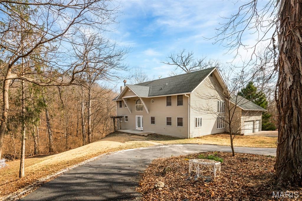 Secluded and surrounded by wildlife with this 2-story home on 2.6 acres. Large front porch welcomes you inside to a high ceiling entry foyer with a sitting area that boasts tons of natural light from the statement window. To your left you will find a room perfect for a library or den with 2 double-sized pocket doors and a beautiful fireplace. Just beyond the living room is a separate formal dining room with French doors that lead out to the back deck. The eat-in kitchen is complete with gorgeous wood cabinetry, ornate lighting fixtures, a center island with breakfast bar, pantry and breakfast room with French doors leading out to the back deck. The massive living room features high ceilings, tons of windows and access to the loft. The oversized loft is nicely set up as a recreational area with a built-in bar and includes a wood-burning fireplace. A convenient half bath is found right off the living room along with an additional room perfect for an office. The upper-level master bedroom suite offers a large walk-in closet and master bathroom with a double sink vanity, walk-in shower and separate soaking tub. There are 3 additional nicely sized bedrooms and a full bathroom with a double sink vanity and tub/shower combo that complete this upper level. Basement is unfinished with tons of potential to finish or just use as extra storage space. The large back deck overlooks a gorgeous backyard with tons of foliage and a pond. A 2-car side entry attached garage and close access to Highway 44 & 55 make this home even more desirable. Do not hesitate to come check out how much living space and privacy this home has to offer!