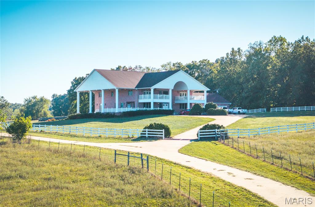 Fischer Farm and Ranch Estate – Turnkey, Multi-Use Property!
This 122+ acre working farm combines productivity, comfort, and self-sufficiency. Designed for livestock, crops, and residential living, the property includes multiple water sources, extensive fencing, and high-quality improvements throughout.

Land and Water Features:
Two ponds, seasonal springs, and a year-round creek provide abundant water. Three wells, six automatic cattle waterers, welded wire perimeter fencing, and cross-fenced pastures make this property livestock-ready. Four pastures, including a smaller barnyard pasture, each have multiple water sources for easy rotational grazing. Vinyl fencing lines the road frontage and surrounds the main home. Concrete driveways provide easy access to barns and home, and a 1,000-gallon diesel tank services machinery.

Barns and Outbuildings:
• Main Barn (“Grandma’s Barn”) – Three apartments (two wheelchair-accessible, one caretaker) with full kitchens, baths, laminate floors, and individual heating/cooling. Common area includes laundry, half bath, gas stone fireplace, overhead garage heaters, multiple garage doors, and overhead storage. Insulated with concrete floor; serviced by owned 1,000-gallon LP tank.
• Hay Barn – Holds 180–190 round bales, concrete floors, working pens, cattle chute, water, electricity, and equipment overhangs. Integrated corral and manure management system streamline livestock handling.
• New Barn (2018) – Insulated with cement floor, overhead doors, water, gas heater, electric panel, and lighting; perfect for machinery or feed storage.

Greenhouse, Root Cellar, and Orchard:
45’x45’ Nexus greenhouse built into hillside supports year-round growing with triple polycarbonate, automatic climate controls, gas heaters, air handlers, irrigation, and raised concrete beds with composted soil. Adjacent root cellar adds storage. Orchard includes peach, apple, plum, cherry, apricot, persimmon, pear, and pecan trees. Garden area features figs, blueberries, currants, blackberries, aronia, and three types of seedless grapes.

Main Residence:
Brick home with 6 bedrooms plus 2 sleeping rooms and 8.5 baths. Main-floor primary suite, four upstairs bedroom suites, and three basement suites (two non-conforming). Each bedroom has a full bath and walk-in closet. Two kitchens and three laundry areas support multi-generational living or staff. Main kitchen includes Viking/Sub-Zero appliances, cherry cabinetry, large pantry, and breakfast bar. Professionally refinished oak floors, tiled entries, and laminate bedroom floors complete the home.

Living areas include cathedral ceilings, gas fireplace, south-facing windows with remote blinds, and French doors to patios overlooking the 22,000-gallon fiberglass pool. Outdoor entertaining is enhanced by patios on three sides, overlooking pastures, ponds, and natural scenery.

Infrastructure and Systems:
Steel-stud construction, Anderson windows, central vacuum, conduit wiring, three geothermal HVAC systems (main replaced 2025), five 40-gallon water heaters plus on-demand unit for master bath. Solar power via 104 SolarEdge panels with net metering. Four 200-amp electrical panels (800 total amps), buried 1,900-gallon LP tank, and cellular booster ensure full functionality.

Summary:
A rare opportunity blending high-quality infrastructure, multi-generational housing, livestock-ready land, and sustainable features. Ideal for cattle, crops, or a full-time rural homestead with income potential. This property is fully equipped for productive living, comfort, and convenience. Schedule your private tour today to experience this one-of-a-kind farm and ranch estate!