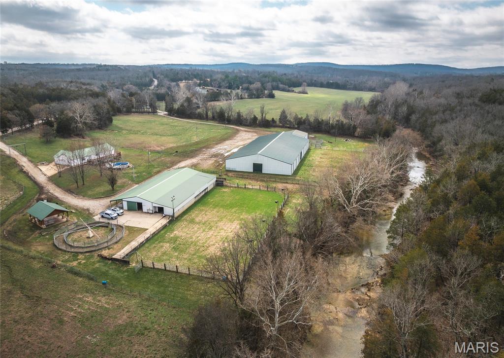 Turnkey equine estate located along scenic Cabanne Course Creek featuring professional-grade facilities, a beautifully maintained ranch-style home, and outstanding income-producing potential. Conveniently located just over an hour from St. Louis and approximately 20 minutes from Park Hills, this property offers a rare combination of privacy, accessibility, and established equestrian infrastructure. The residence offers approximately 3,640 m/l square feet with 3–4 bedrooms, multiple baths, and a warm rustic feel throughout. Hardwood floors, updated finishes, vaulted ceilings, a cozy fireplace, and two spacious living areas create a comfortable setting for both everyday living and hosting guests. A walkout basement and dedicated mud/laundry room add convenience for an active ranch lifestyle. Designed with versatility in mind, this property is exceptionally well suited for a variety of equine and event-based business opportunities. The impressive 200' x 100' red-iron indoor arena/event center features lighting, a sound system, concession area, and restrooms with showers, making it ideal for year-round barrel races, team ropings, rodeos, horse shows, clinics, riding lessons, auctions, and special events. A 210' x 100' lighted outdoor arena provides additional space for competitions, training, and large-scale gatherings. Supporting facilities include a 120' x 60' metal barn with 18 horse stalls, wash bays, tack rooms, and ample storage, creating an excellent setup for horse boarding, training programs, breeding operations, lesson programs, or a full-service equestrian business. A 4-horse hot walker further enhances the property's appeal for serious horse owners and trainers. The well-maintained pipe fencing, cross-fenced pastures, and automatic waterers provide efficient livestock and pasture management while offering ample turnout space for horses. A pavilion and fire pit create a welcoming atmosphere for competitors, spectators, and guests during events. Whether your vision is a premier barrel racing facility, rodeo venue, horse boarding operation, training center, event destination, or private equestrian retreat, this property offers the infrastructure and location to support a wide range of opportunities. Facilities of this caliber are increasingly difficult to find, and the replacement cost of the arenas, barn, fencing, and supporting improvements would be substantial.