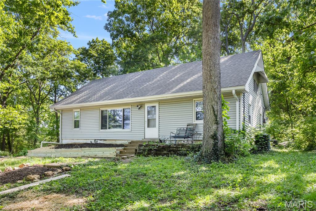 Discover the perfect balance of privacy and convenience in this charming home nestled on a lush, wooded lot. Enjoy a peaceful, “staycation” lifestyle every day, surrounded by nature while still being close to everything you need. The spacious living room is filled with natural light from a large picture window, offering beautiful views of the expansive front yard. Out back, a private, tree-lined setting creates your own quiet retreat. The main level features stylish luxury vinyl plank flooring, along with a well-appointed kitchen complete with stainless steel appliances and ample workspace—perfect for any home chef. You’ll also find 2 comfortable bedrooms and a full bath on the main floor. A convenient side-entry mudroom serves as a functional hub with laundry and additional storage. Upstairs, a rustic staircase leads to a bright, airy loft enhanced by skylights—ideal for a home office, library, or creative space. The upper level also includes flexible sleeping quarters that can easily function as 2 bedrooms(sellers use as multiple bedrooms), along with a full bath featuring a built-in seated shower. Located in unincorporated Fenton near Gravois Bluffs, this home offers a rare opportunity to enjoy peaceful, wooded living with nearby amenities. Property is being sold as-is with seller to do no repairs. Put your handyperson to work and make this your dream home. Schedule your showing today and make this serene retreat your next home!