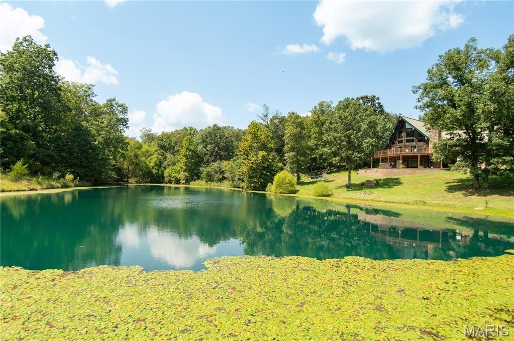 Escape to your own private Ozark retreat at 17492 BCR 314 in Marble Hill, Missouri! Situated on 13 +/- acres, this beautiful 3-bedroom, 3-bath A-frame home with a full finished basement offers the perfect combination of privacy, comfort, and country living. As you approach the home, you'll immediately notice the inviting wrap-around porch and large picture windows overlooking the beautiful private pond, home to bass, crappie, and panfish. The pond also features its own natural overflow waterfall that comes alive and flows vigorously after a good rain, adding to the beauty and character of the property.

Inside, the main level features tall ceilings, a thoughtfully designed open-concept layout, and beautiful custom woodwork that continues into the kitchen cabinetry. The spacious kitchen offers a large island, plenty of cabinet and counter space, and a beautiful stone fireplace that creates a warm and inviting atmosphere. The oversized laundry room offers tons of storage, a wash tub, and convenient access from the attached two-car garage. The lofted primary suite provides privacy and begins with an open sitting area featuring amazing views through the picture windows, making it the perfect spot for morning coffee. The primary bedroom also features its own custom bathroom with double vanity sinks, a custom tiled shower, and ample storage.

The finished basement is built for entertaining with a large open area currently used as a movie room, a full kitchen, full bathroom, and an additional room that could serve as a bedroom. The basement also features a beautiful stone fireplace, making this space perfect for gathering with family and friends. Step outside from the basement and take in the beautiful views of the pond while enjoying the luxury of your own hot tub.

The property also offers a 25x35 shop, cross-fencing, and a history of being used as a mini farm with Highland cattle. Wildlife is a daily part of life here, with deer and turkey frequently seen from the home and deck. The acreage also offers an excellent opportunity for hunting, making this an appealing property for the outdoorsman. Whether you're looking for a private homestead, recreational retreat, or simply a place to slow down and enjoy the Ozarks, this property brings country living and comfort together. Schedule your showing before this one is gone!