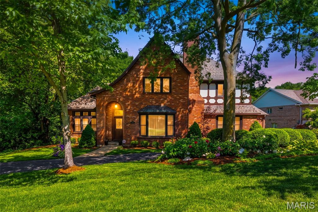Open Sunday 8/23 1-3 PM!!  This magnificent brick Tudor-style estate resides across the street from Watson Trail Park and sits on a breathtaking, private 0.51-acre wooded lot in prestigious Sunset Hills, truly your own private botanical garden oasis. Boasting an impressive 5,356 square feet of luxurious living space, this home showcases timeless elegance with exceptionally spacious, generously proportioned rooms throughout.
The main level impresses with a massive living room featuring a cozy fireplace, an equally expansive family room with fireplace and convenient half bath just off it, formal dining room perfect for entertaining, and a gourmet eat-in kitchen complete with a large breakfast bar, center island with prep sink, and electric cooktop. Additional main floor highlights include a dedicated office, a sunroom with built-in hot tub, and convenient main floor laundry. Rich oak woodwork, soaring beamed ceilings, and extensive custom built-ins add warmth, character, and sophistication.
Upstairs, the  large primary bedroom suite offers a luxurious primary bath, complemented by three additional very spacious bedrooms and a full bathroom. The huge walk-out basement features a full bath, providing exceptional flexibility for recreation, guests, or future expansion.
Step outside to enjoy the expansive deck and patio overlooking the serene, lush backyard, an entertainer’s dream in a peaceful, park-like setting.
Nestled in the highly sought after Lindbergh School District, this exceptional residence offers the perfect blend of classic Tudor charm, modern comforts, and resort-like private grounds. A truly rare opportunity. Welcome home!