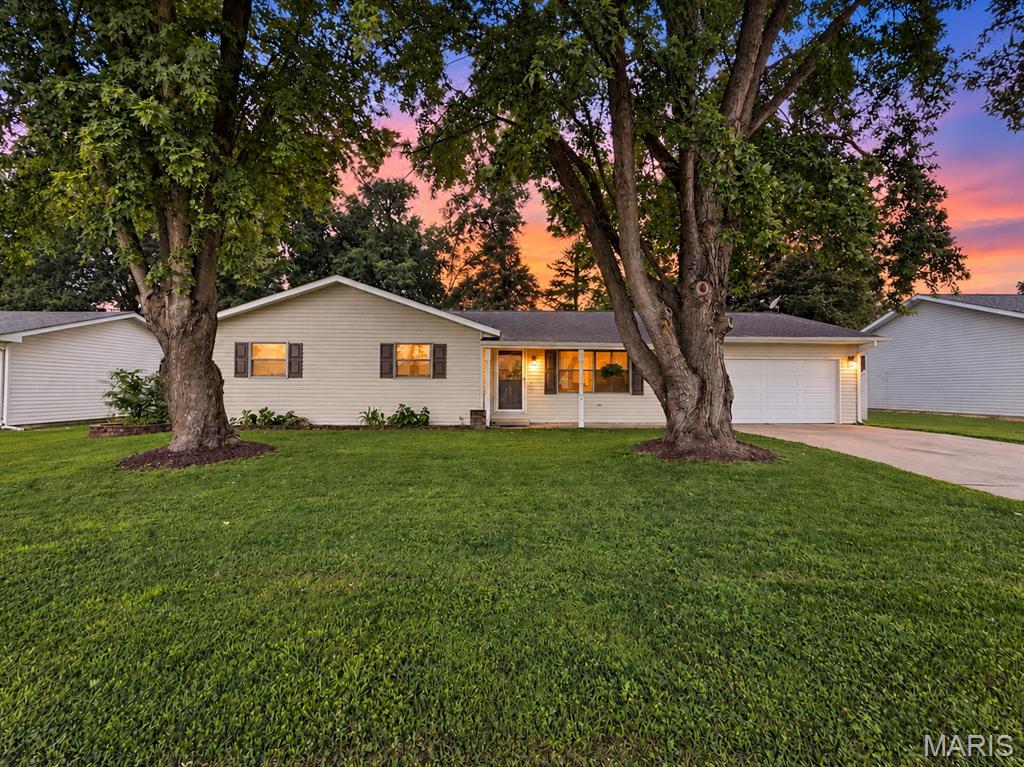 The street's named Leisure. The house lives up to it. Pull up to 403 Leisure and the first thing you notice is shade. Two mature trees out front, standing there longer than most of the houses around them. Walk in and it opens up. Vaulted ceilings over the main living area. Brick fireplace anchoring the room. Clean sight lines from the front window all the way back to the kitchen. Nobody cooks alone in this house. Whoever's at the stove is still in the conversation. Out back is where it earns its keep. Paver patio sized for the grill. Wood deck with string lights already hung. Privacy fence. Big shade tree in the corner of the yard. It's the kind of backyard where an ordinary Friday runs two hours long. Fire pit going, kids running, nobody in a hurry to leave. Day to day, here's what makes it work. 1,454 square feet, all on one level, not one wasted foot. Three bedrooms, two full baths. The primary is a true suite, private bath and glass door shower. Two more bedrooms down the hall with the second full bath, and one of them, shiplap accent wall and all, is set up as an office right now if you don't need the third. The kitchen is bright and crisp. White cabinetry, black hardware, tile backsplash, white appliances that stay. Vinyl plank flooring that handles boots, dogs, and spilled coffee without flinching. Main floor laundry right off it with a utility sink and cabinet storage. No hauling a full basket up and down stairs. Ever. Two car garage, finished and lit up bright, with pull down attic access for the totes you only touch twice a year. Storage shed out back for the mower and the lawn gear. At this size storage is usually the problem. Here it isn't. Short commute to Scott AFB. Truly move in ready, in a town people actually want to be in, at a price that still makes sense.nClean, updated ranches in New Baden don't linger. They never do.