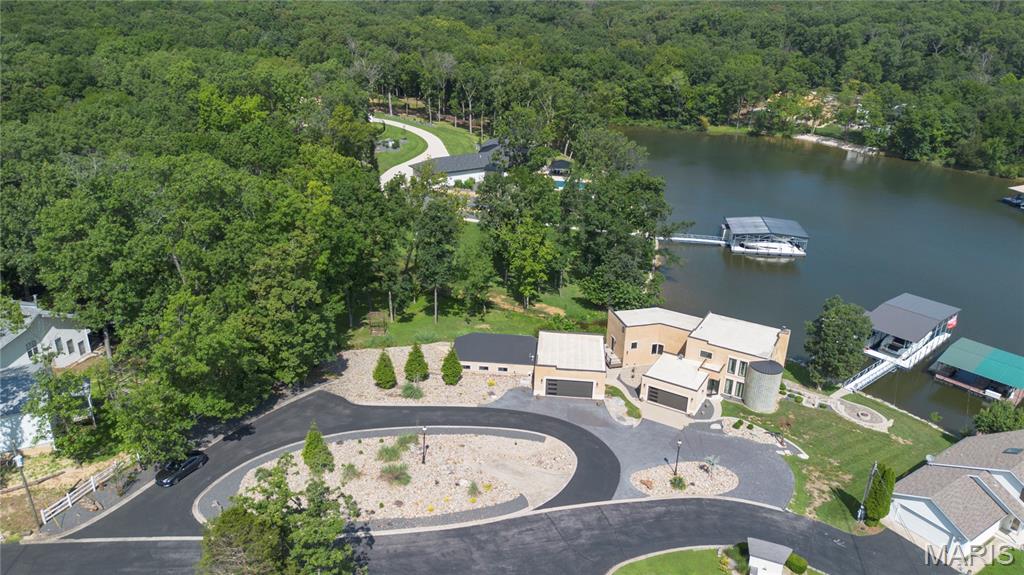 Discover luxury lakefront living at its finest with this fully furnished, completely updated home. Designed for effortless entertaining and everyday comfort, this 5-bedroom, 4 full/2 half bath property showcases high-end finishes and a spacious, open-concept layout. Step into a beautifully redesigned interior featuring a dream kitchen with premium appliances, custom cabinetry, and sleek countertops. Sophisticated touches include dramatic spiral staircase, modern marble flooring, and designer lighting. The walk-out lower level adds even more space for hosting, relaxing, or enjoying lake views year-round. Outside, the gentle, landscaped lot leads you to your own private lakefront oasis. Enjoy a custom outdoor kitchen, expansive patio, and a private dock equipped with an 18’x50’ slip, PWC slip, and lift all perfectly positioned in a peaceful cove. A rare and valuable bonus to this property is the guest house, with indoor swimming pool for year-round enjoyment. Whether you're searching for a full-time lake residence, a weekend escape, or an investment property, this remarkable home delivers top-tier luxury, unmatched amenities, and the very best of Lake of the Ozarks lakefront living.
