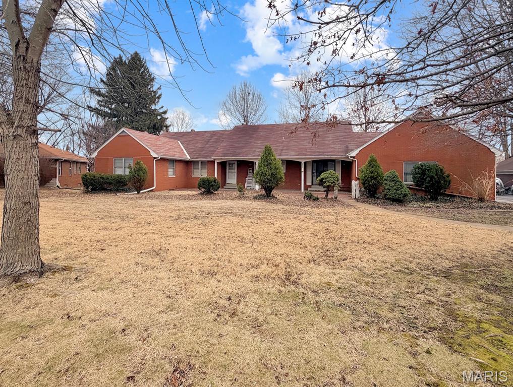 This brick ranch sits on a 0.6-acre lot in Wesley Place Subdivision and has had only two owners in its lifetime. The second owner, a skilled handyman, maintained the home conscientiously for decades — the house has some retro finishes, but the bones are sound and everything works as it should. The neighborhood of Wesley Place is quietly convenient. The grade school, public library, park, police department, and fire department are all within two blocks. St. Louis is a 20 minute drive. Main Level: Hardwood floors run through the main living areas. The living room has a brick fireplace and a picture window with good natural light. The kitchen features a breakfast bar and connects to a dedicated dining area. A bonus room off the main level has exterior access and works well as a home office or formal dining room. Four bedrooms are located down the hallway. The primary bedroom has dual closets and an ensuite full bathroom. Basement: The full basement is partially finished and includes a second fireplace and a vintage bar. Additional spaces include a large room with a closet, a 3/4 bathroom, a laundry room with a utility sink and storage cabinets, and a workshop with a workbench and built-in shelving. A staircase connects the basement directly to the attached two-car garage. Attic & Outdoor Space: The unfinished attic runs the full length of the home and offers substantial storage or the potential to be finished into additional living space — one of several ways this property lends itself to expansion or modernization for the right buyer. Outside, the lot gives you room for gardening or yard activities, and a storage shed is included for lawn equipment. Mechanicals: The major systems have been updated in recent years: air conditioning replaced in 2016, furnace in 2025, and water heater in 2026.