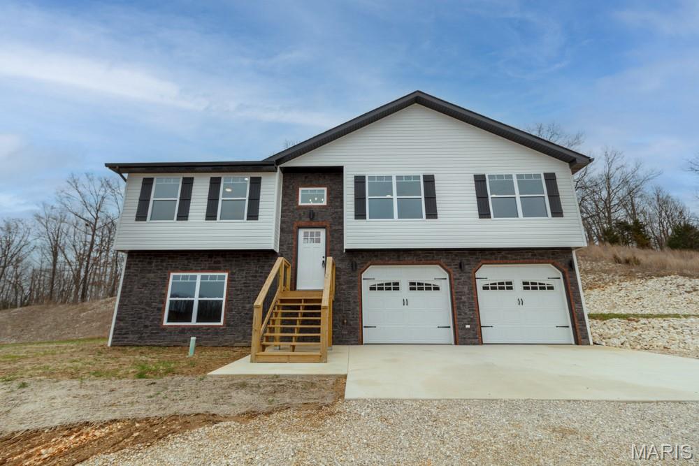 Beautiful new construction 4-bedroom, 2.5-bath home offering two living areas and an open-concept layout. This quality-built home stands out with custom upgrades you won’t find in a typical spec home. Enjoy high-end luxury vinyl plank flooring throughout the living areas, bedrooms, and kitchen.The kitchen features solid wood cabinetry with under-cabinet and toe-kick lighting, granite countertops, and a large center island. The living room is filled with natural light and showcases a tray ceiling with wood beams and shiplap accents that continue into the dining area.Solid wood mocha stained trim is carried throughout the home, adding a modern, cohesive look. The primary suite offers two closets and a private bath with a spacious tiled walk-in shower featuring both wall and rain shower heads.The finished basement includes a family room with shiplap accent wall, an additional bedroom, half bath, and laundry area. A large garage with twin 8-ft doors adds extra convenience. Exterior features include stone, brick, and vinyl siding, plus a 12x12 rear deck.Located just 10 minutes from Fort Leonard Wood. Seller offering a $3,500 appliance allowance at closing for buyer to pick appliances and have them installed after closing—don’t miss this opportunity!