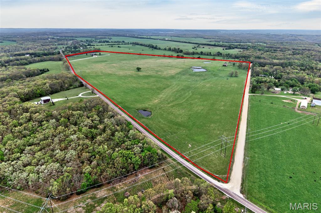 Set on 112+ acres of lush, fully fenced countryside, this distinguished brick estate offers an exceptional blend of refined interior living and expansive outdoor opportunity. Thoughtfully designed with both elegance and functionality in mind, the home welcomes you with impressive 12-foot ceilings and beautifully appointed gathering spaces throughout. The formal dining room showcases marble flooring, creating a sophisticated setting ideal for hosting. At the heart of the home, the kitchen features a large center island, granite countertops, a Jenn-Aire stove, and a designated breakfast area with hardwood flooring, providing both everyday comfort and elevated entertaining space. Just beyond, the family room with an electric fireplace offers a warm and inviting retreat, while the formal double-sided sitting room adds timeless character and versatility. The spacious primary suite includes his and her closets and a luxurious ensuite bath complete with double vanity, jetted tub, separate shower, and an elegant crystal chandelier-a true private sanctuary. Additional highlights include an oversized laundry room with sink and extra storage, hardwired smoke detectors throughout the home, and enhances wall insulation for comfort and efficiency. Practical upgrades continue beneath the home with a 4-foot lighted crawlspace, and peace of mind comes with a brand new roof just recently installed within the last month. The surrounding acreage-fertilized just last year-offers beautiful, productive land ideal for livestock, recreation, or simply enjoying the serenity of wide open views. A rare opportunity to own a refined country estate with acreage, privacy, and thoughtful upgrades throughout. Call us to schedule your showing today to see if this could be YOUR next home!