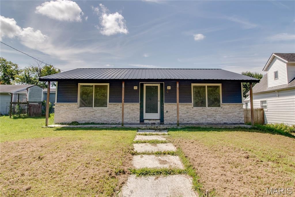 This partially renovated 2-bedroom, 2-bathroom ranch-style home was built in 1990 and sits on a 0.1722-acre lot. Exterior features include vinyl siding, a metal roof installed in 2023, and a private backyard with a rear deck installed in 2023 and distinctive metal fencing installed in 2024. A long covered front porch welcomes you into a bright, open main living area. Large front windows bring in natural light, while neutral finishes, recessed lighting, ceiling fans, and continuous vinyl plank flooring create a clean, cohesive look. The kitchen features brand-new cabinetry and flows into the dining and living spaces, creating a flexible setting that can be completed and arranged to suit the buyer’s needs. Two bedrooms feature neutral carpeting. Both bathrooms have ceramic tile flooring, with portions of the renovation work remaining to be completed. A convenient combination mudroom and laundry area provides a main-floor laundry hookup. Convenient alley access leads to concrete and asphalt parking. Electric service is connected, with public water and sewer readily available. Several interior projects remain to be completed. All building materials currently at the property will remain, giving the buyer a head start on completing the improvements and selecting finishing touches that suit their style. Property is being sold as-is. Schedule your showing today to explore everything this home has to offer.