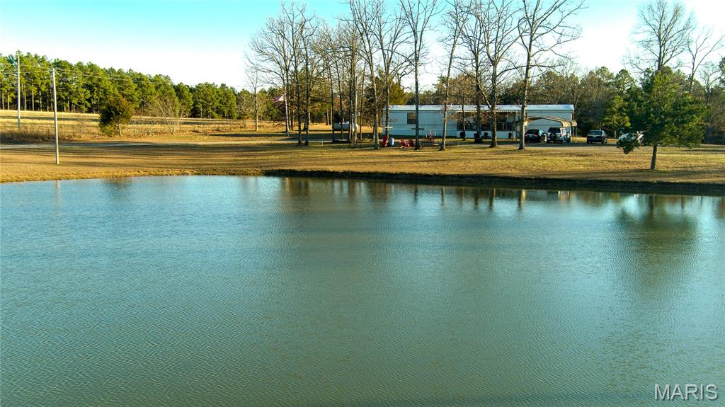 Discover country living with a park-like setting on 12 acres and a large pond stocked with catfish, perch, bass and carp. 3 bedroom, 2 bath Champion model home was built in 2000 and has 1,120 sq. ft. of living space.  24' x 14' covered porch that overlooks the pond. Eat-in kitchen with wood cabinets, gas range and refrigerator. Split floor plan with 2 bedrooms and one bath off of the living room and a primary bedroom with full bathroom off of the kitchen. Laundry area. Propane heat and central air. Drilled well and lagoon. 2 propane tanks stay with the property. 18' x 20' carport. 40' x 8' box trailer and a small chick coop. Partial fencing. 16' above ground pool. Perfect weekend retreat or full-time homestead. Great property for the buyer who wants land and outdoor fun. conveniently located near Salem, Rolla, Ft. Leonard Wood and Licking. Home is selling AS IS. CALL FOR A SHOWING!