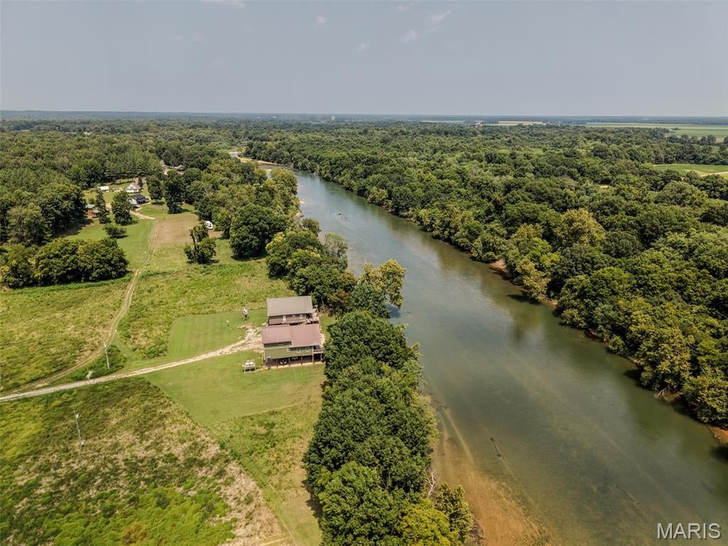 534 Swift Water Trail, Maynard, Arkansas - Experience effortless riverfront living at this sharp custom-built 1.5-story home situated right on the banks of the iconic Current River. Spanning over 2,600 sq. ft., this 3-bedroom, 2.5-bathroom residence features solid flooring, handmade cabinetry, custom tiled showers, foam insulation and a tankless water heater—crafted for  efficiency and low maintenance inside and out. Ideal as a full-time sanctuary or a weekend retreat, the home is being sold fully furnished and turnkey. Step outside onto the full width east-facing deck for cool afternoon shade and panoramic river views after a day on the water. Complete with a concrete boat launch and pavilion just a few hundred feet away, plus the invaluable peace of mind of having stayed high and dry during the 2017 flood, this property is ready for immediate enjoyment. High speed internet installed.