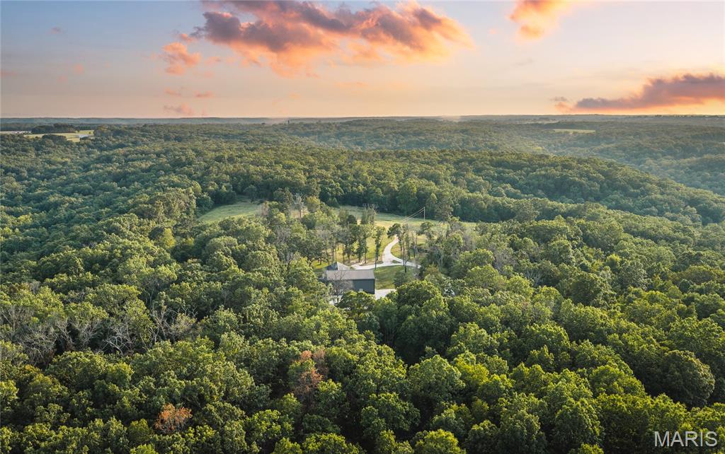 Here is your chance to own something truly special—a property that must be seen and explored to fully appreciate. Built in 2022, this luxury barndominium sits on 50.5 surveyed acres and offers an exceptional combination of high-end country living, privacy, recreation, hunting, and convenient access to Lake of the Ozarks. Located near Climax Springs, this incredible estate provides the peace and privacy of the Ozark countryside while keeping the lake and nearby amenities just a short drive away. Whether you're looking for a full-time residence, private retreat, hunting property, or multi-generational family compound, this property offers the space, quality, and flexibility to make it possible.

A private drive winds through mature timber before opening to a beautiful hilltop setting overlooking the property's pasture. Built in 2022 with no expense spared, the approximately 2,650+/- square-foot barndominium features 3 bedrooms, 2.5 baths, spacious main-level living, and additional second-story living space. High-end finishes include luxury LVP flooring, quality carpeting, radiant floor heat, a tank-less water heater, Starlink high-speed internet, a ZLINE convection oven, and a beautiful custom kitchen.

The property also includes an impressive 1,728+/- square feet of garage and shop space, providing plenty of room for vehicles, boats, side-by-sides, tractors, and equipment. The oversized space can accommodate an exceptionally large RV or even a Greyhound-sized bus, while multiple exterior RV hookups provide additional options for guests, family, or extended stays.

Outside, a beautifully constructed stamped-concrete, hand-framed covered patio overlooks the pasture and provides the perfect setting to enjoy spectacular Ozark sunsets. From here, you can watch deer, turkey, dove, hummingbirds, and other wildlife utilizing the property. A 1/3 basketball court with regulation goal, abundant parking, and plenty of open space add even more opportunities for family recreation and entertaining.

The 50.5 acres are a major part of what makes this property so special. Mature, rolling timber ridges surround the hilltop pasture, creating privacy, scenic views, and excellent wildlife habitat. A spring-fed creek winds through the bottom ground, offering exceptional opportunities for morel mushroom hunting, Indian artifact hunting, and exploring the natural beauty of the property. An established trail system and small food plots provide access throughout the acreage while enhancing the property's recreational and hunting potential. With a proven hunting history and numerous deer and turkey harvested over the years, this is a property where you can truly enjoy the outdoors right outside your door.

The acreage also offers tremendous potential for a multi-generational family compound. With multiple desirable building locations, there is room for additional residences, guest quarters, or future homes for children, parents, or extended family. Create a private family homestead where multiple generations can live together while maintaining their own space.

When it's time to enjoy the lake, Lake of the Ozarks is just a short drive away, putting boating, fishing, swimming, dining, and recreation within easy reach. Here, you truly get the best of both worlds—peaceful country living with convenient access to one of Missouri's premier recreational destinations.

If you're looking for a property where you can live comfortably, hunt out your back door, enjoy the lake, entertain family and friends, keep all your equipment under one roof, and create a family compound for generations to come, this incredible 50.5-acre Ozarks estate deserves a serious look. This isn't simply a home—it is an opportunity to build a lifestyle and a legacy on your own piece of the Missouri Ozarks.