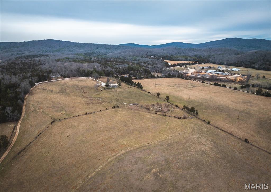 Tucked away just off Highway E in Madison County, this 100 acre farm offers a rare combination of usable pasture, timber, year-round live water. Properties that blend this level of privacy with convenience and natural beauty are becoming increasingly difficult to find. Here, you’re surrounded by the quiet of the countryside while enjoying direct access to the Mark Twain National Forest and being only a short distance from Marble Creek recreation area — a setting that delivers the full Missouri outdoors experience right outside your door.

The land lays exceptionally well, with approximately 60 acres of open, productive pasture ideal for cattle, horses, or hay production. The remaining acreage is composed of rolling hardwood timber, providing excellent wildlife habitat and endless recreational opportunities. Nearly 0.85 mile of Marble Creek frontage traces the western boundary, offering clear, flowing water, exposed rock shelves, and scenic stretches perfect for fishing, wading, or simply relaxing along the bank. The combination of open ground, timber, and live water makes this property equally suited for a working farm, a hunting and recreation getaway, or a long-term family retreat.

The main residence is a 3-bedroom, 1-bath ranch home with nearly 2,400 square feet of living space. Inside, you’ll find a comfortable layout with a partially finished basement that includes a bath rough-in, offering the potential for additional bedrooms, a second living area, or expanded storage. Multiple heat sources — including an outdoor wood furnace, a propane furnace, and fireplace — ensure efficient and reliable comfort throughout the seasons.

Supporting the homestead are several functional outbuildings, including a detached garage, multiple barns, and equipment sheds. These structures provide ample room for machinery, tools, hay, and general farm operations. Everything is already in place for a smooth transition into livestock production or hobby farming, with fenced pastures, working pens, and plenty of storage.

A second residence sits nearby, offering valuable flexibility. It’s ideal for rental income, guest accommodations, or multi-generational living — a rare advantage for those seeking a property that can serve multiple families or provide supplemental revenue.

Large acreage with live water, improvements, and direct national forest access seldom becomes available in this part of Missouri. Whether your vision is agricultural, recreational, or residential, this farm provides the space, resources, and setting to make it possible.