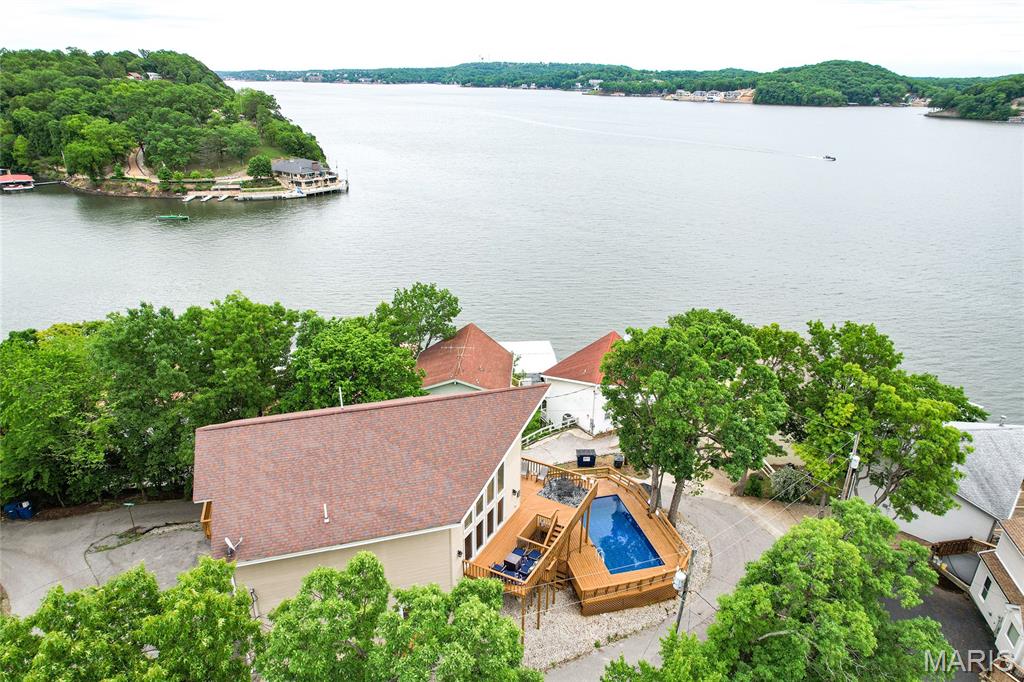 Some lake homes check boxes. This one creates a feeling. From soaring ceilings and walls of windows to the large lakeview decks, a pool positioned to make every day feel like a vacation, and unforgettable views. This 3,490 sq ft, 5-bedroom lakefront home on the 5MM has the space, layout, and setting to host beautifully OR perform as an income-producing lake retreat.The open living area is bright and dramatic, while the lower level adds wet bar, walkout access, and flexible guest space. The lakefront lot included is a great place to put your own dock, or continue using the slip with a shared dock agreement. $78k in annual vacation rental income for 2025, and already $60k+ for 2026...and more bookings for the rest of July and August. By water, you are close to lakefront restaurants, coves, marinas, and fun making this part of the lake so loved. Major updates include roof and HVAC replacement within the last 4 years, with front windows and front siding scheduled for replacement in August 2026. Add a 2-car garage (being used as flex-space/game room), plenty of parking for guests, lakefront, pool, and beautiful views make this one impossible to ignore. MORE PICTURES COMING!