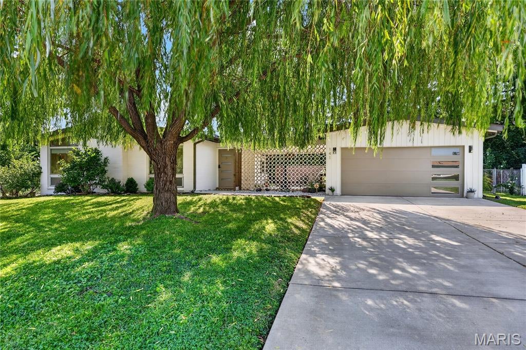 Per the original newspaper ad in 1959, The Fiesta was "probably the utmost in originality." Nearly seventy years later this mid century modern atomic ranch still carries every bit of it, starting with the circular breeze block screen that makes its case before you ever reach the front door.

This house still has the features the era is loved for, and it still has them where they belong. Clerestory windows carry daylight across the living room all afternoon. The ceiling vaults to an exposed beam. Custom wall units flank a floor-to-ceiling painted brick fireplace set on a raised terrazzo hearth. Sputnik and globe fixtures hang where they were meant to hang, a wood slat divider screens the hall without closing it off, and the hardwood floors have been refinished throughout.

The kitchen was reworked to hold those same clean lines rather than fight them, with flat-panel cabinetry, butcher block counters, a turquoise tile backsplash, a wall oven and cooktop, and a peninsula with seating under a pair of globe pendants. It opens straight into a sixteen by thirteen office and sitting room, a genuinely useful flex space with wall-mounted shelving and its own door out to the patio.

Three bedrooms sit together on the main level, all with hardwood underfoot. The primary has a full wall of closets and a renovated private bath with a walk-in shower, a skylight, a floating wood vanity, and a heated towel bar. The hall bath goes the other direction on purpose, pairing blue tile and a navy mosaic floor with a clean modern vanity.

Downstairs, a thirty-five by twenty-five recreation room carries new flooring, recessed lighting, and built-in shelving, with a separate storage room and the laundry alongside it.

Out back, the covered patio repeats the breeze block screen from the front entry, strung with cafe lights over concrete and framed by privacy fencing and ornamental grasses. The level lot runs just over a third of an acre, fenced and backing to mature woods, with an established apiary along the rear edge. A two car attached garage sits off a wide driveway. The mature weeping willow in the front yard is one of a kind, and it is not something a new build can offer you at any price. The subdivision pool is a short walk away and hosts community events through the summer.

The sellers have also replaced the main stack and the sewer lateral, which now carries a new pipe liner, along with the driveway and walkway, the garage door, and the front door.

NEW ROOF (2022), NEW HVAC SYSTEM (2023), NEW WATER HEATER (2020), REPLACEMENT WINDOWS (2018), SUMP PUMP AND FRENCH DRAIN (2019), NEW ELECTRICAL PANEL (2013), NEW SKYLIGHT (2016), CLOSET SYSTEMS (2021).

Schedule your tour today.