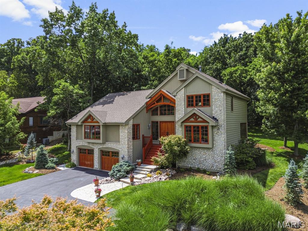 Showings begin Thurs 6/11 at 10AM. Nestled against a lush, wooded backdrop in Wildwood, this extraordinary custom residence evokes the feeling of a private luxury ski retreat—bringing mountain-inspired architecture and resort-style warmth to one of St. Louis County’s most desirable and convenient locations. Completely redesigned by award-winning local architect Lauren Strutman and rebuilt from the ground up in 2000, the home was thoughtfully crafted for the buyer who appreciates distinctive design, exceptional craftsmanship, and a home that feels truly one-of-a-kind. Dramatic rooflines, artisan stonework, exposed wood detailing, and expansive custom windows create a striking architectural presence reminiscent of an upscale retreat in Colorado. A dramatic two-story foyer creates an unforgettable first impression, featuring grand double mahogany entry doors, custom windows that flood the space with natural light, and a stunning custom staircase that immediately showcases the home’s architectural character and craftsmanship. Built with entertaining in mind, the home features an open, flowing floor plan anchored by a dramatic vaulted great room with a gracious floor-to-ceiling stone fireplace and an inviting walk-behind bar—creating the perfect setting for everything from intimate gatherings to large-scale entertaining. Walls of glass flood the living spaces with natural light while framing beautiful views of the lush backyard and surrounding woods. The main-floor primary suite offers a luxurious and private retreat, while three additional bedrooms and an upper-level bath provide comfortable accommodations for family or guests. The thoughtful layout balances everyday livability with ideal spaces for hosting and gathering. The kitchen is both functional and beautifully designed, featuring custom-built, furniture-quality cabinetry paired with all-new Bosch cooking appliances installed in 2026. Just off the kitchen, a large stamped concrete rear patio extends the living and entertaining space outdoors—ideal for dining al fresco, hosting guests, or simply enjoying the peaceful wooded backdrop. Rich wood tones, organic textures, and curated finishes throughout the home create an atmosphere that feels luxurious yet deeply inviting—equal parts sophisticated and relaxed. This is the kind of home that instantly transports you, offering the feeling of vacation living every single day. The home has also been thoughtfully updated with a completely gut-renovated primary bath completed in 2026, delivering a spa-like retreat worthy of a five-star resort. Situated on a beautifully landscaped .63-acre lot backing to woods, the outdoor setting feels lush and serene, with plenty of space to relax, entertain, or explore. An invisible fence allows dogs to roam freely throughout the yard, making the property as functional as it is beautiful. Rarely does a home so successfully combine architectural significance, warmth, convenience, and everyday livability. For the buyer who has always dreamed of owning a home inspired by their favorite mountain getaway—without leaving Wildwood—this is a truly exceptional opportunity.